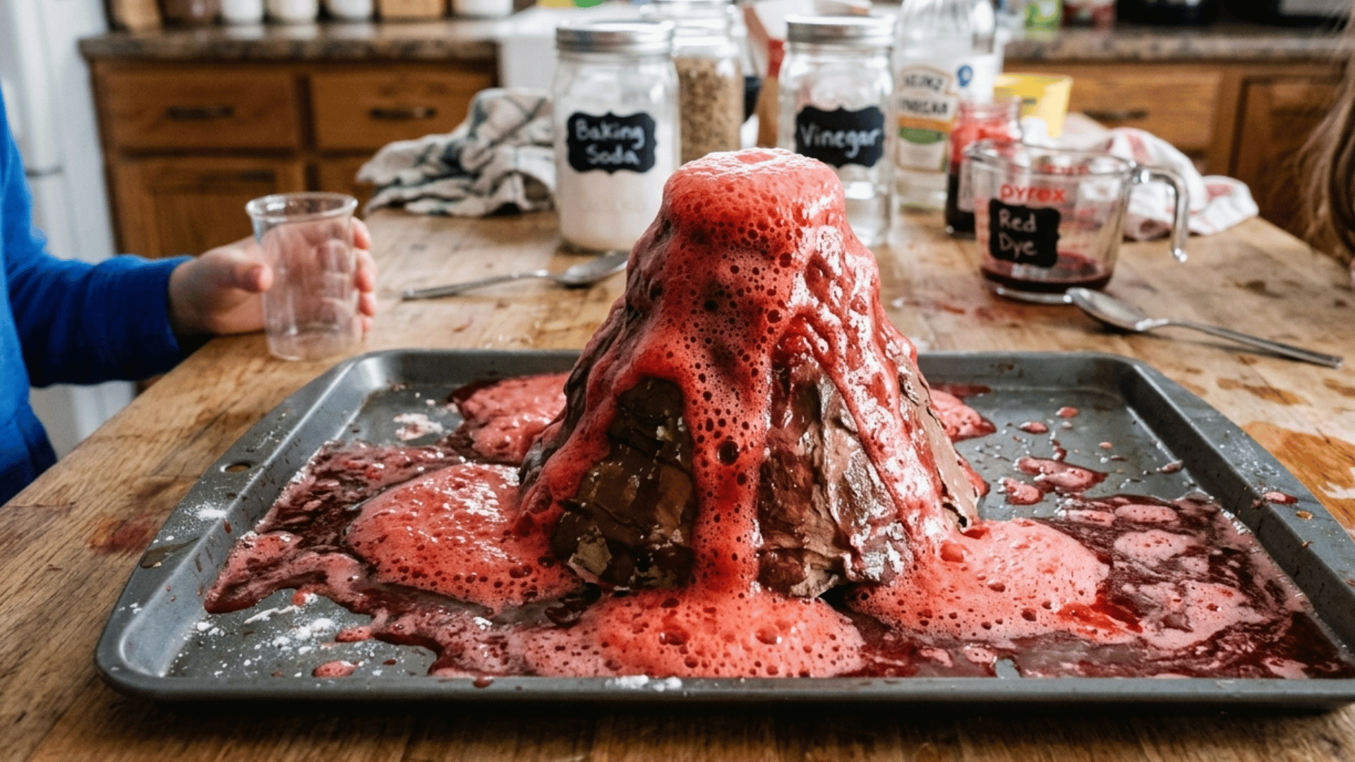 baking soda volcano experiment erupting with red fizzy foam on a tray