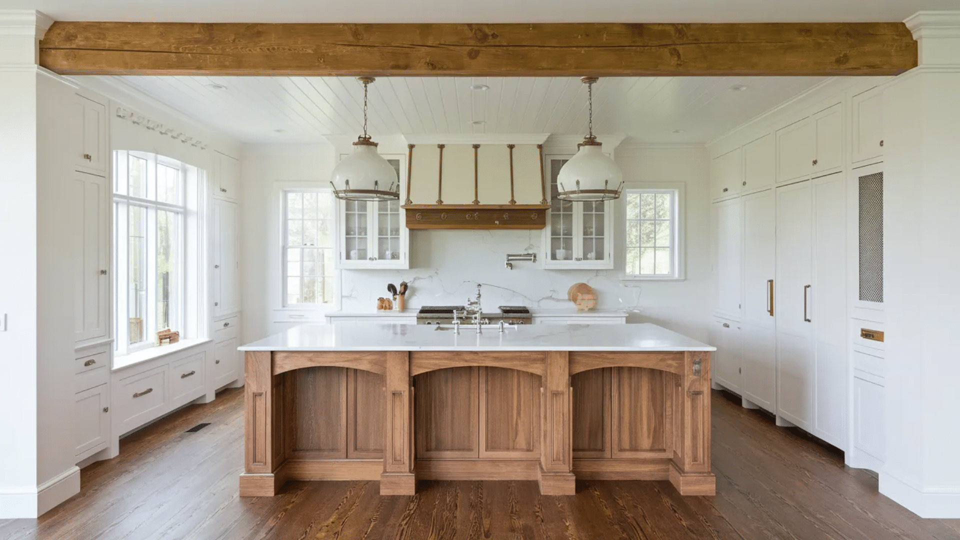 bright white farmhouse kitchen with large wooden island pendant lights exposed beam marble backsplash and tall cabinets