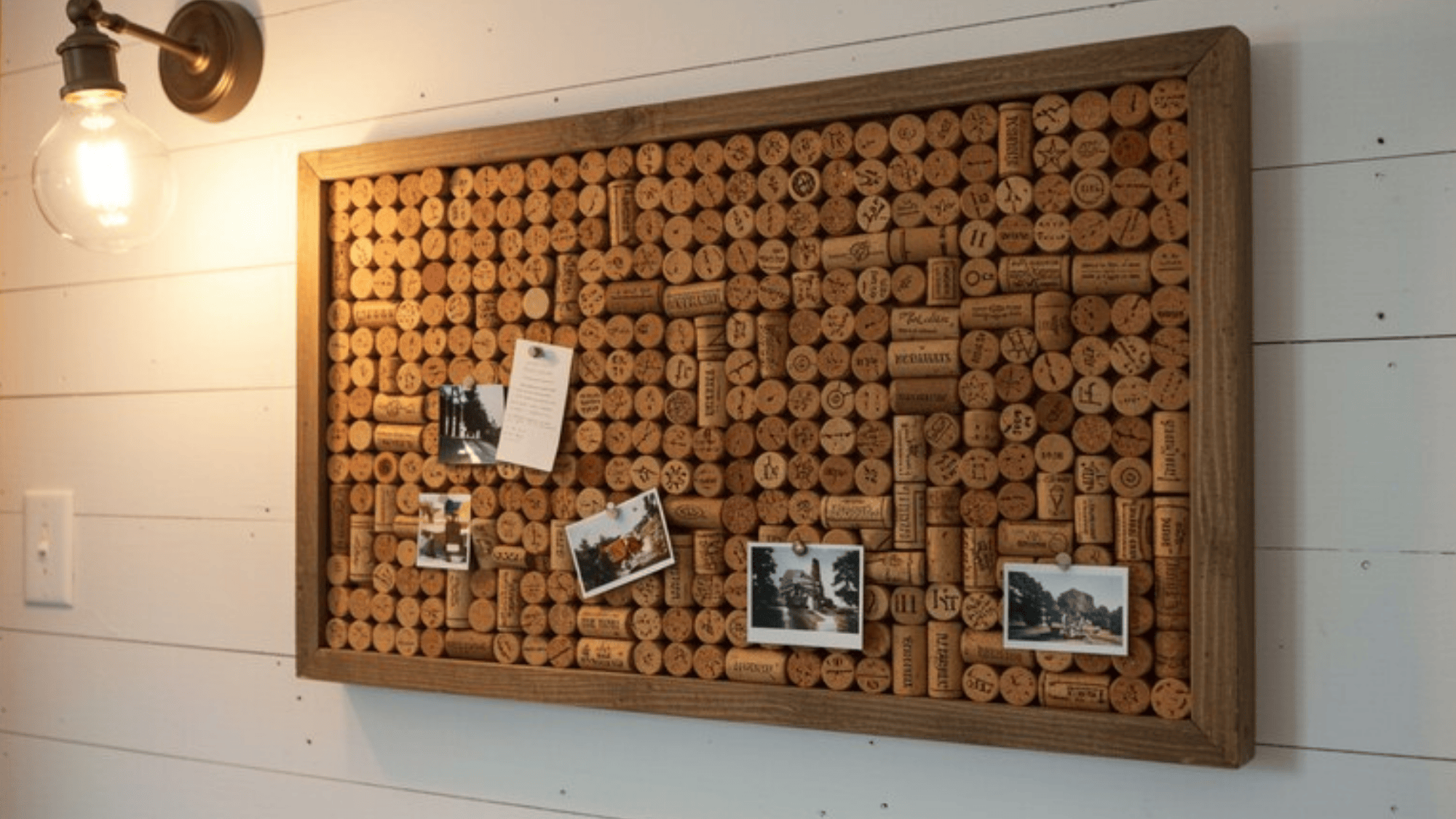 bulletin board made of wine corks inside a wooden shadow box, small photos and notes pinned to it