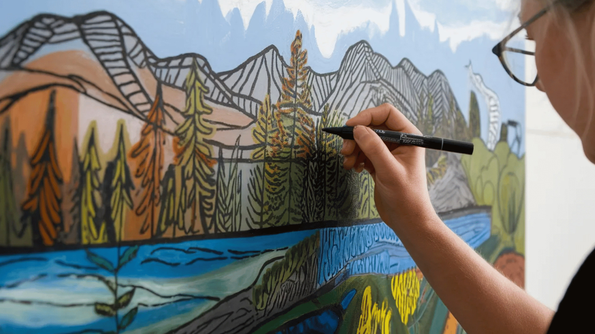 close up of an artist's hand adding fine details with acrylic paint markers