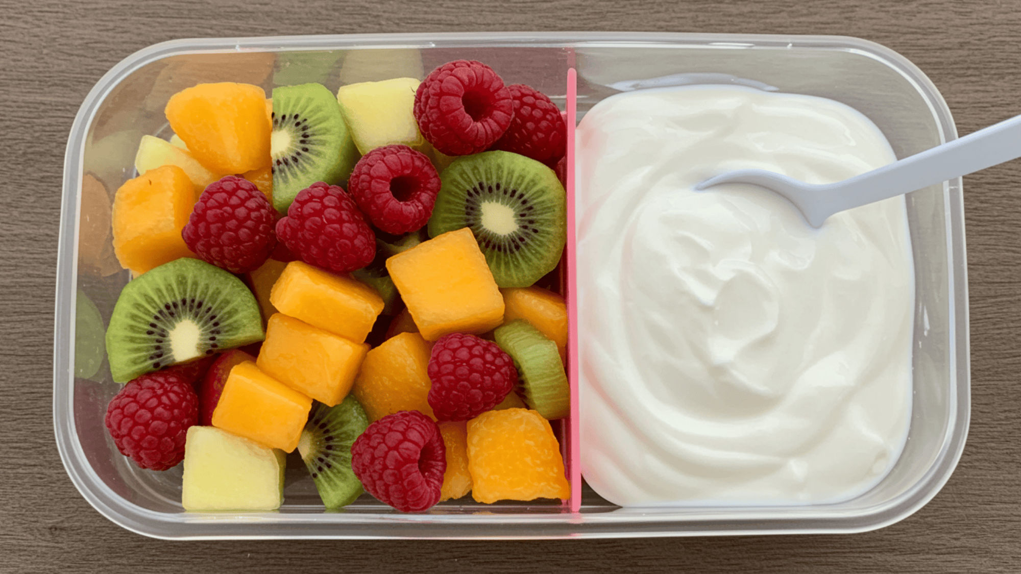 colorful fruit salad with diced strawberries, kiwi, blueberries, and mango, paired with creamy Greek yogurt in a lunchbox