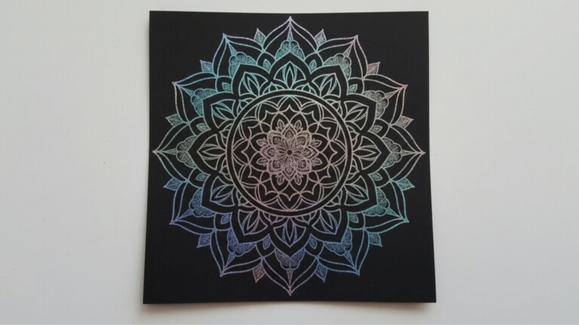 colorful mandala artwork on black canvas with intricate symmetrical patterns and gradient hues displayed on a wall
