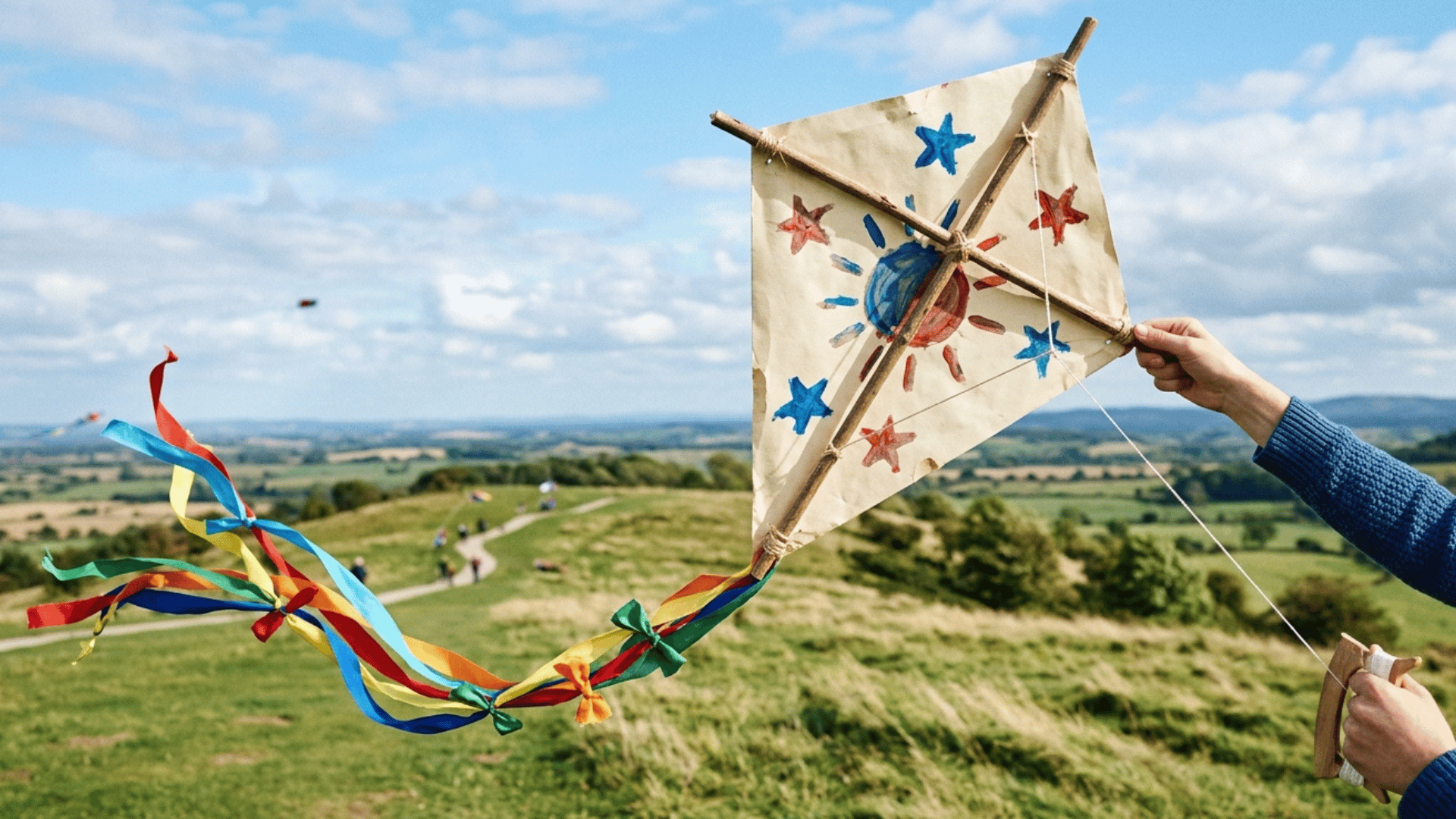homemade kite made with sticks, paper, and ribbon tail ready to fly outdoors