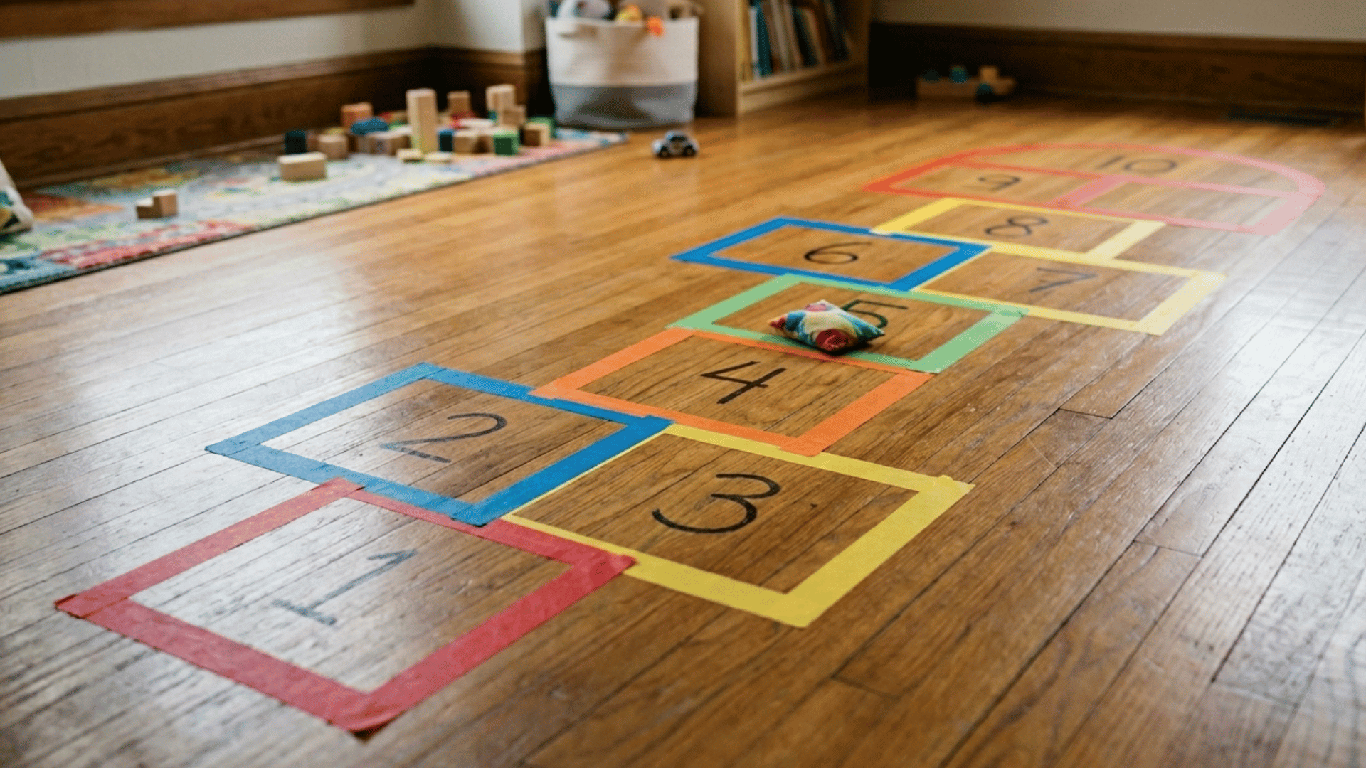 indoor hopscotch grid made with tape on the floor for kids play at home