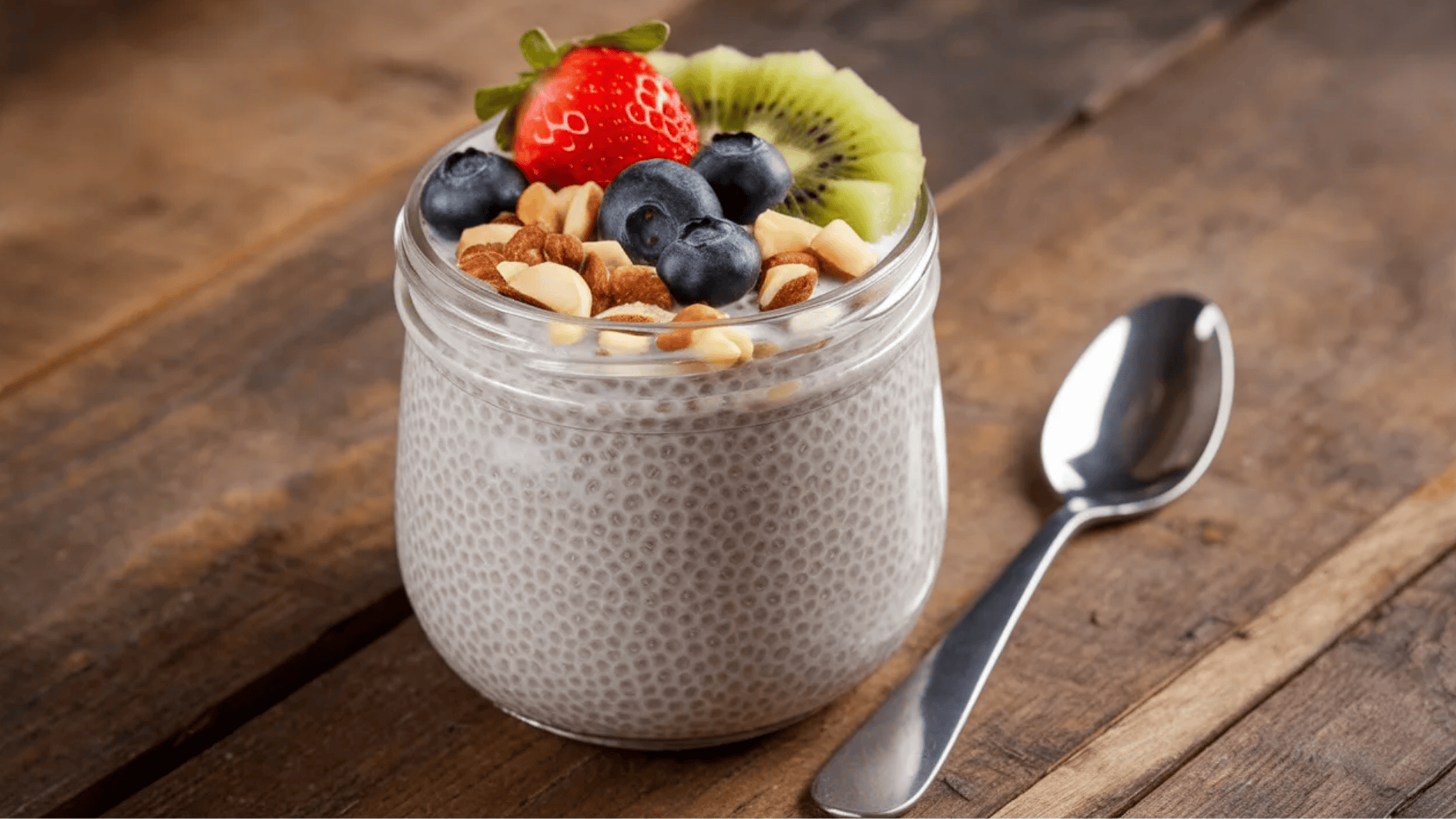 jar of chia pudding topped with fresh strawberries, blueberries, kiwi slices, and chopped almonds