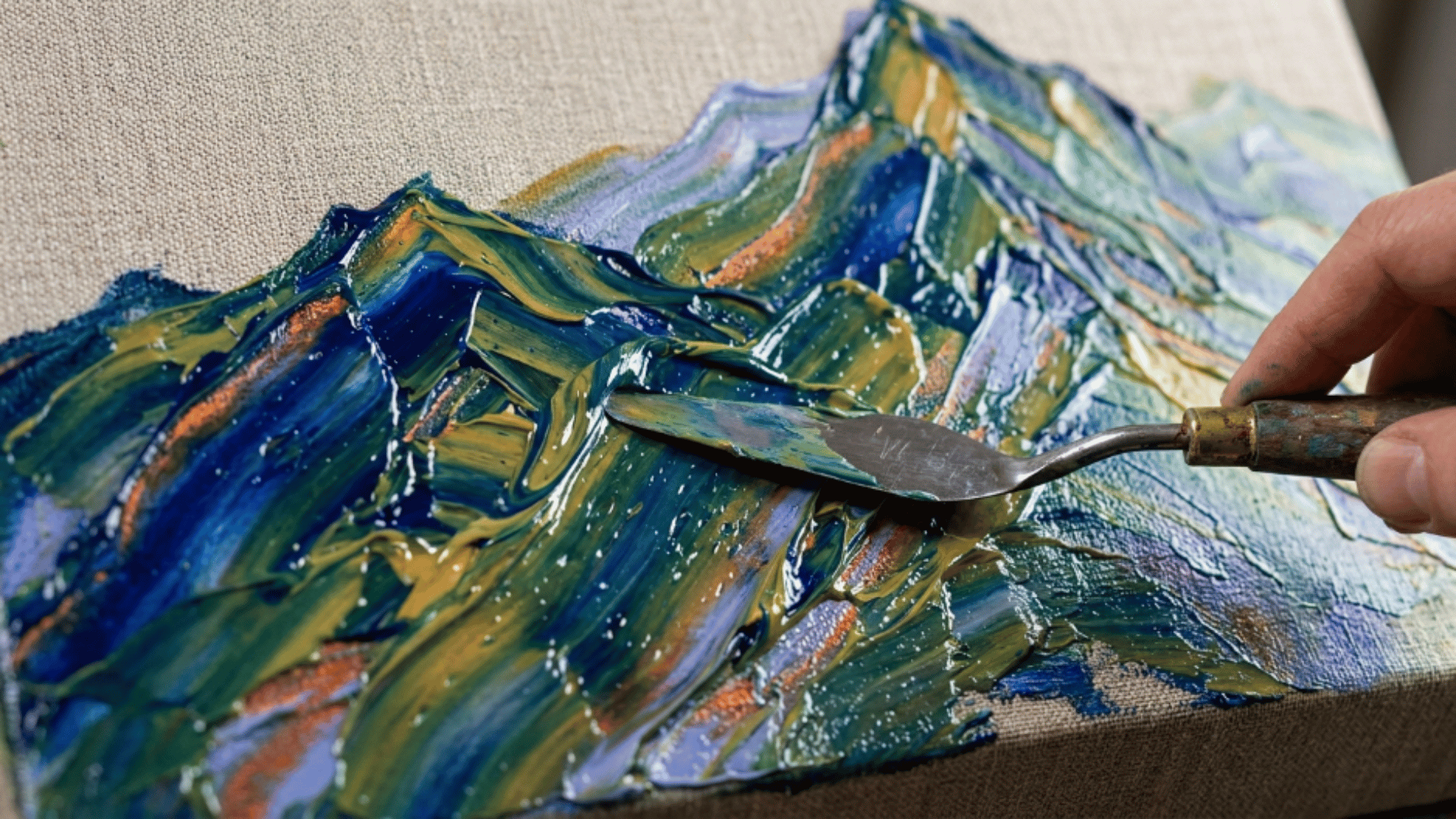 palette knife spreading thick acrylic paint across canvas forming textured abstract mountain shapes