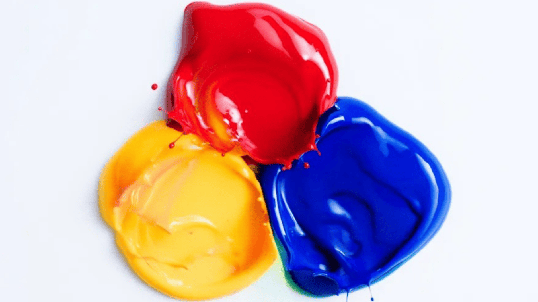 primary colors of red, yellow, and blue paint mixed on a white surface, creating splashes