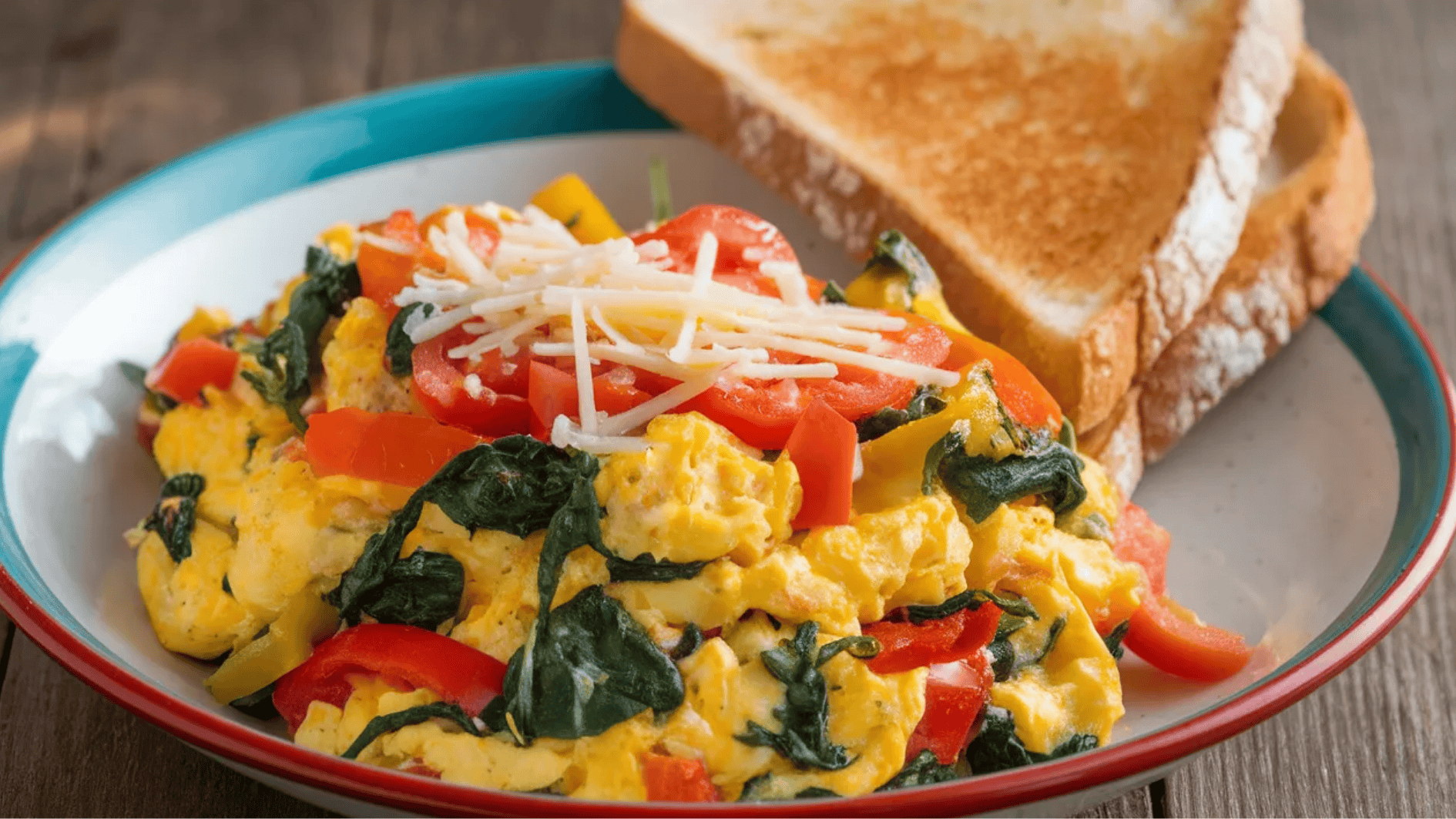 scrambled eggs with spinach, tomatoes, and a side of toasted bread.