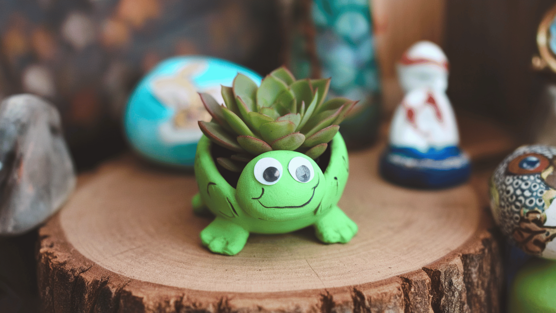 small green-painted clay pot with googly eyes, plant or succulent inside, resembling a turtle shell.