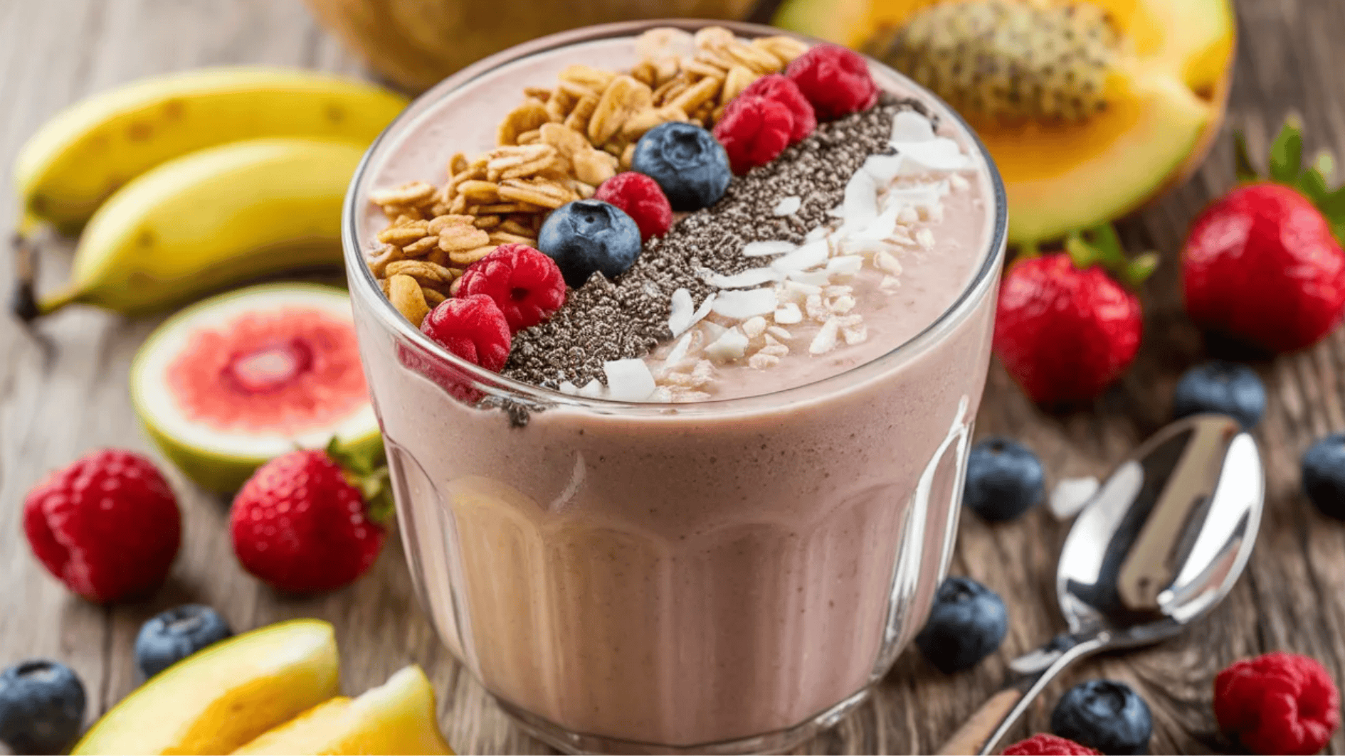smoothie bowl topped with granola, raspberries, blueberries, chia seeds, and coconut flakes, with banana slices nearby