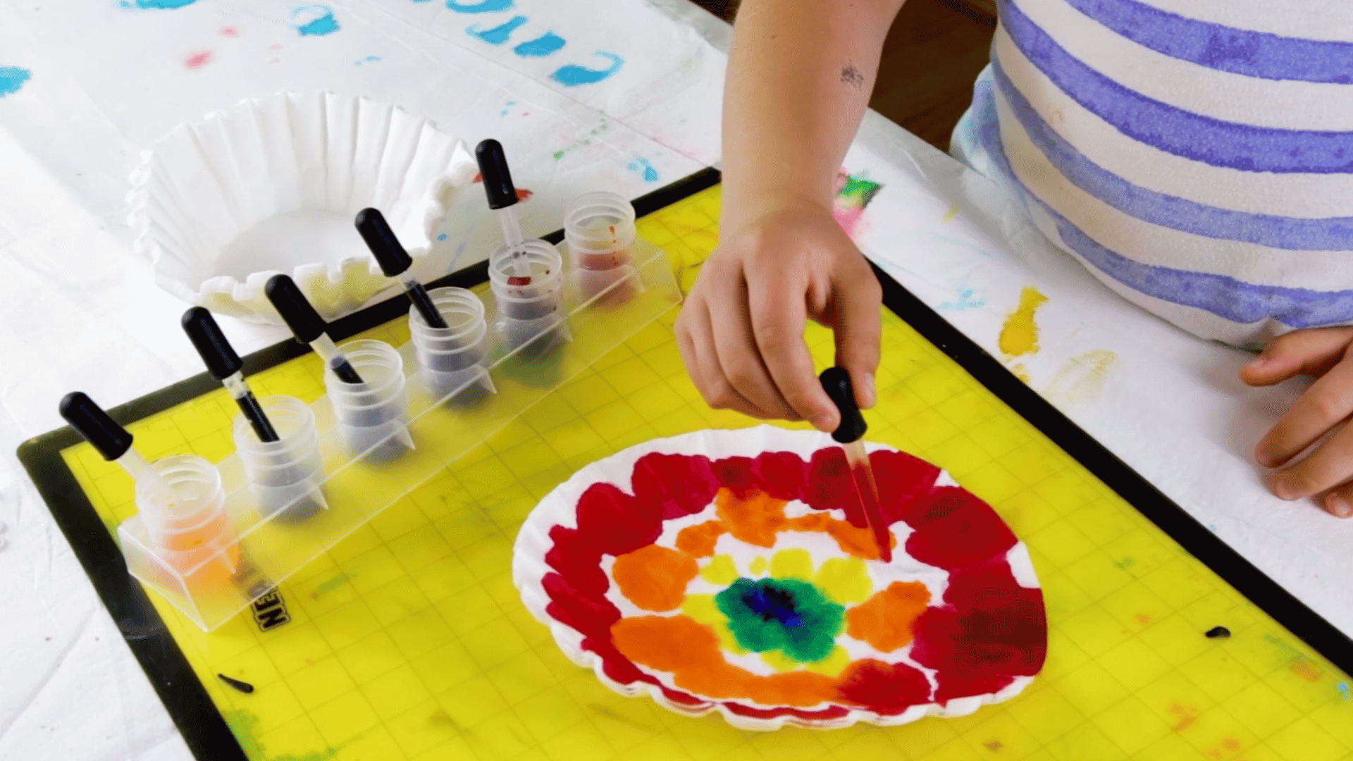 using a dropper to apply liquid watercolor paint onto a coffee filter.