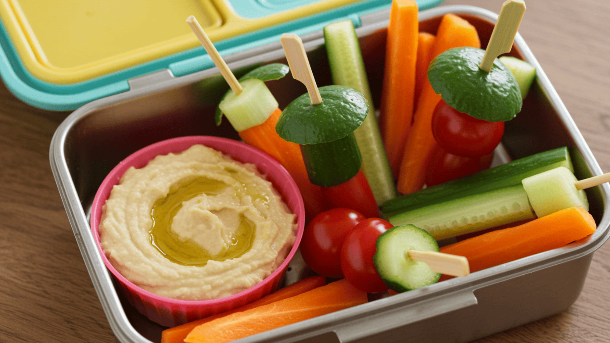veggie skewers dipped in hummus, arranged as pops in a lunchbox, colorful bell peppers and cucumber