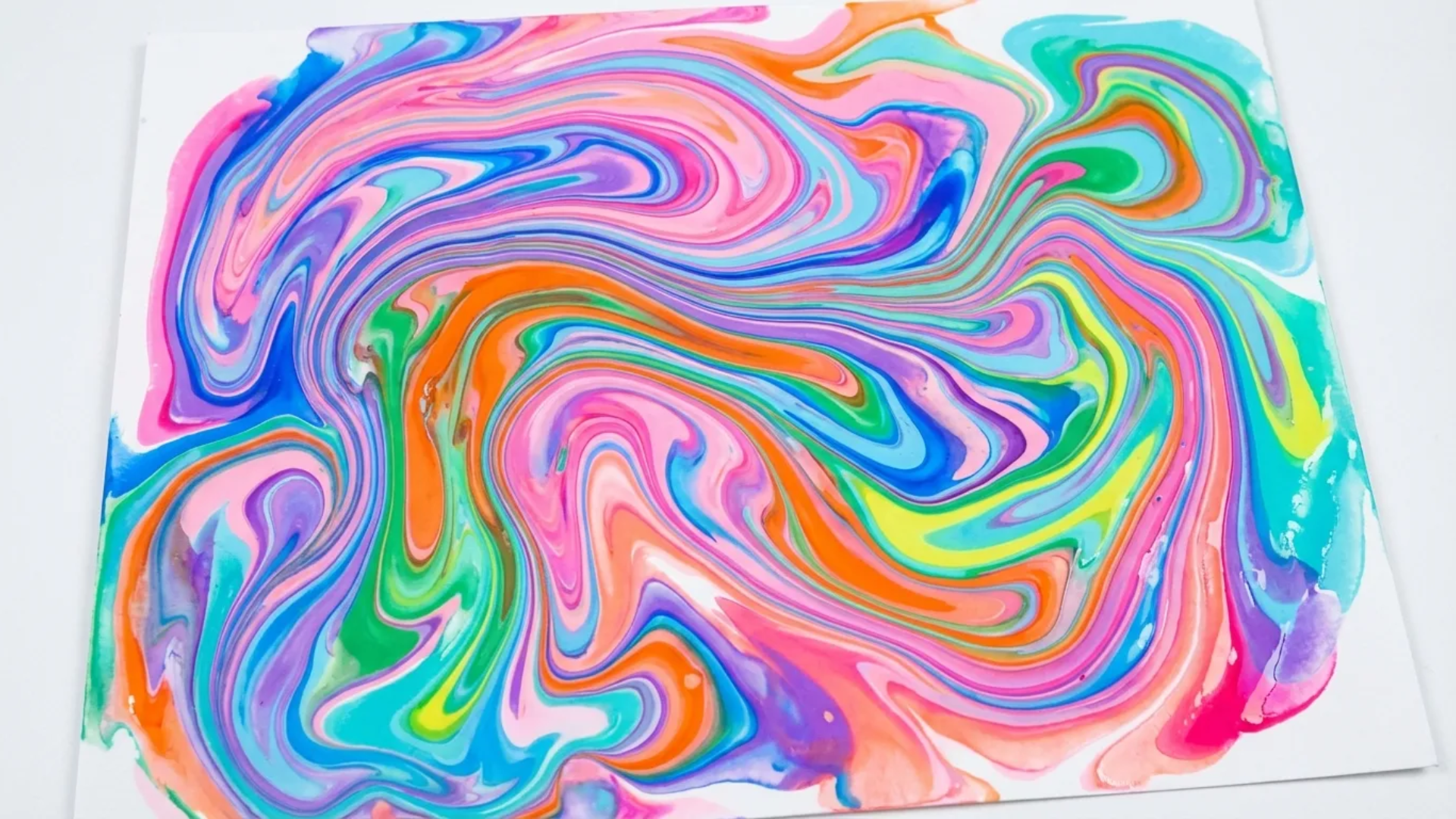 wavy intersecting blue and pink paint trails on white paper made by rolling paint covered marbles in a box