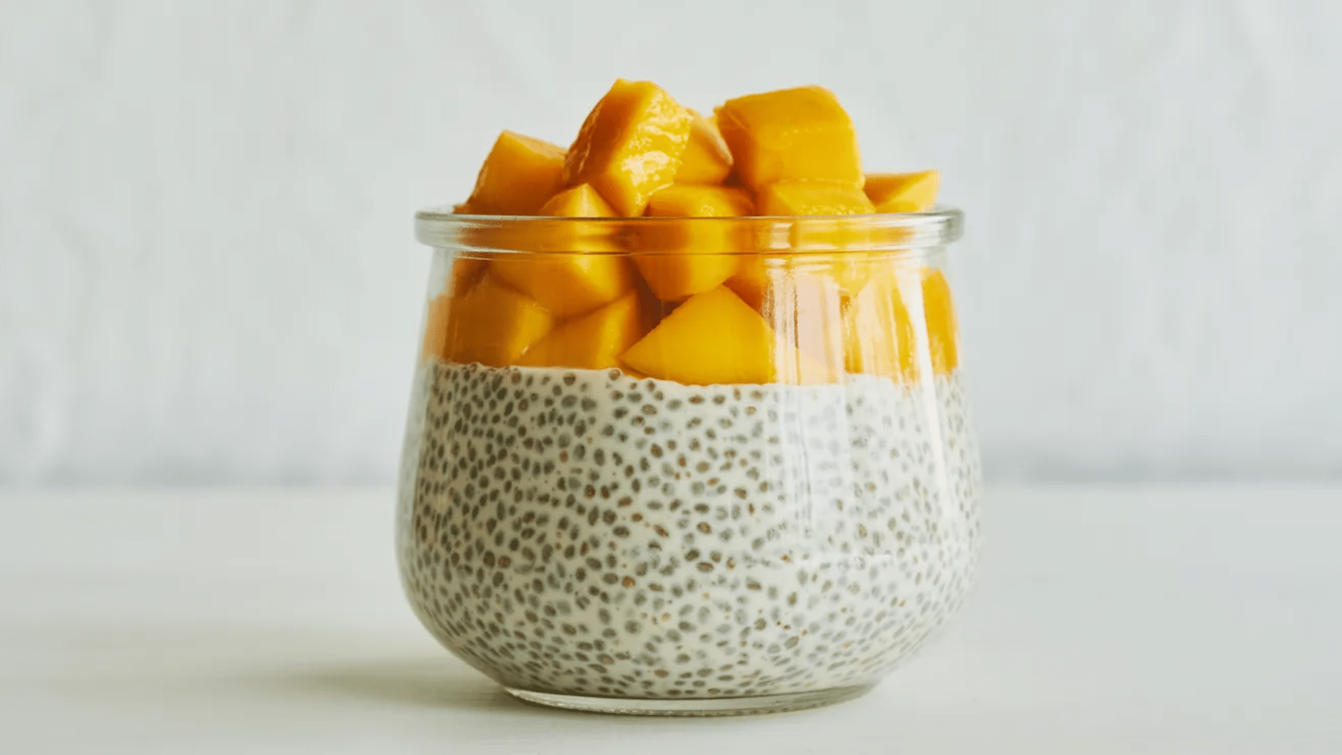 chia pudding topped with fresh mango chunks in a glass jar