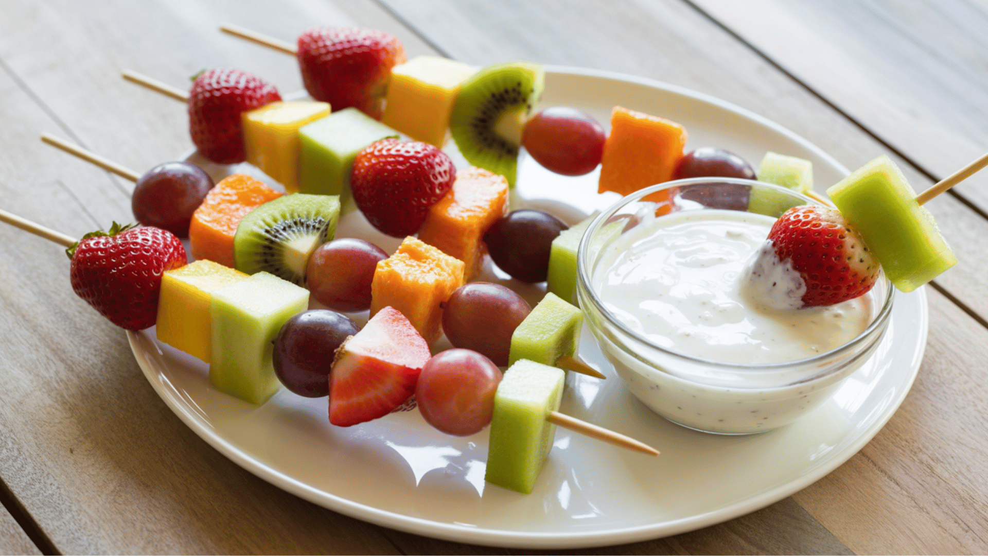 colorful fruit skewers with strawberries, grapes, melon, and kiwi on small sticks