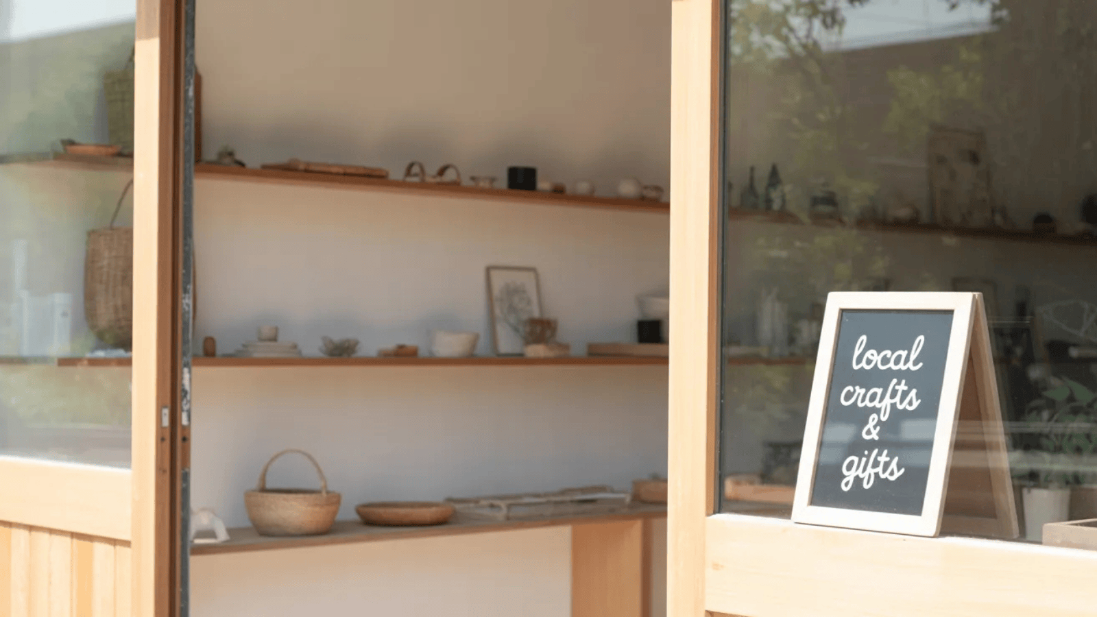 cozy storefront of a small craft shop with wooden shelves, handmade goods, plants, and a welcoming minimalist aesthetic