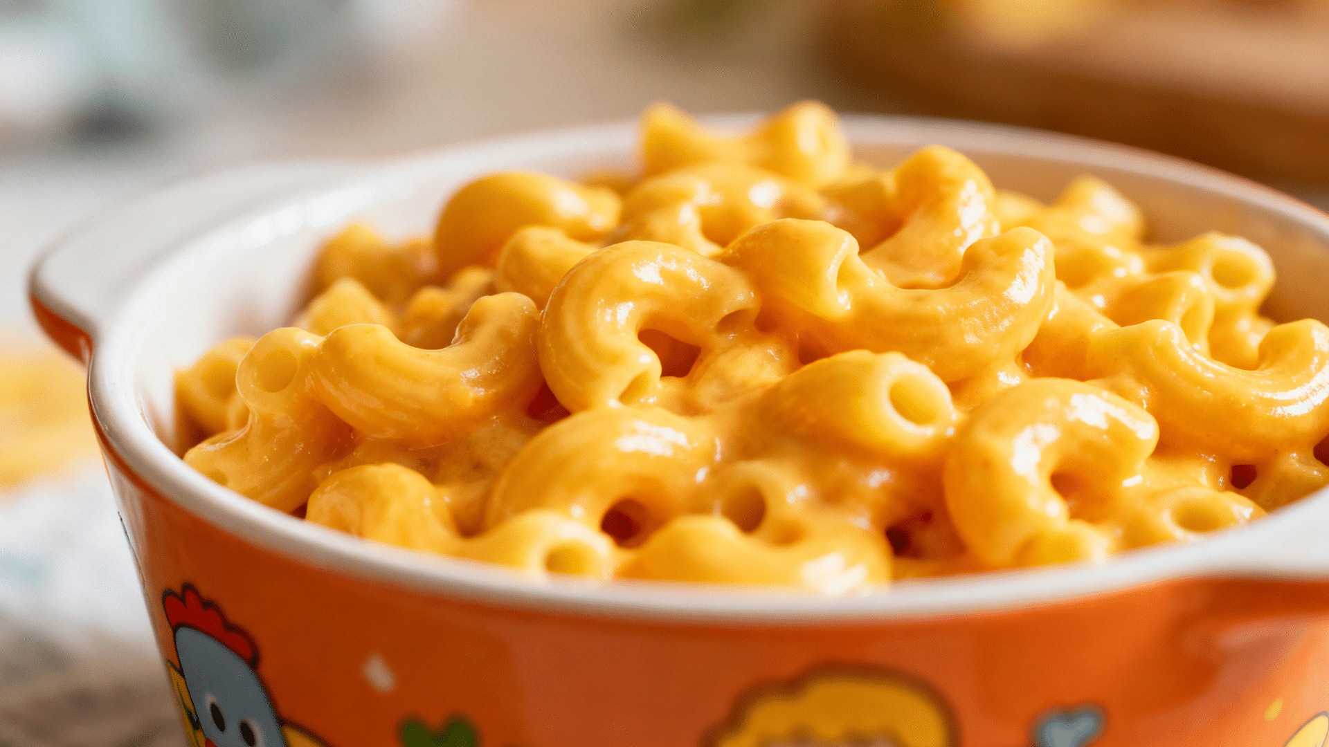 creamy macaroni and cheese with glossy melted sauce served in bowl with warm lighting and soft background blur