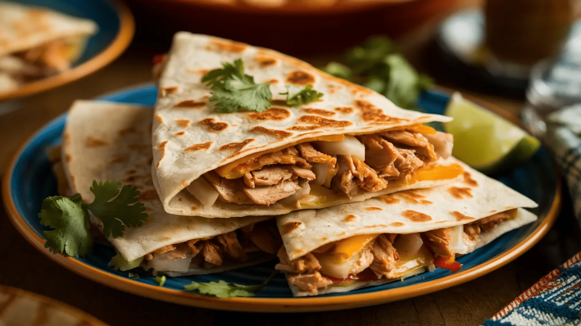 grilled chicken quesadilla folded and filled with cheese and meat served on a plate with lime wedges and herbs nearby