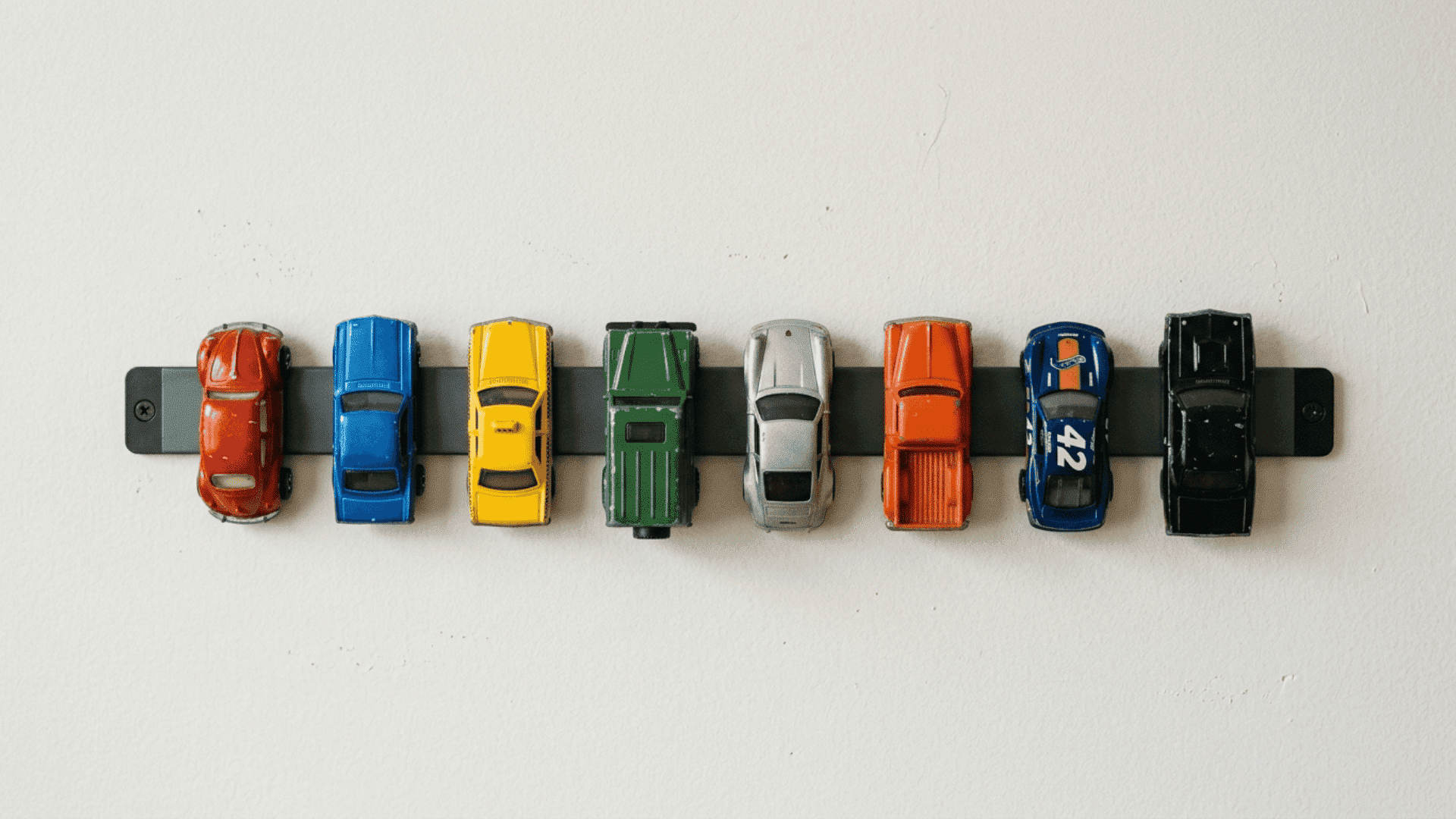 magnetic strip on wall holding small toys in visible organized way to prevent clutter in a compact playroom