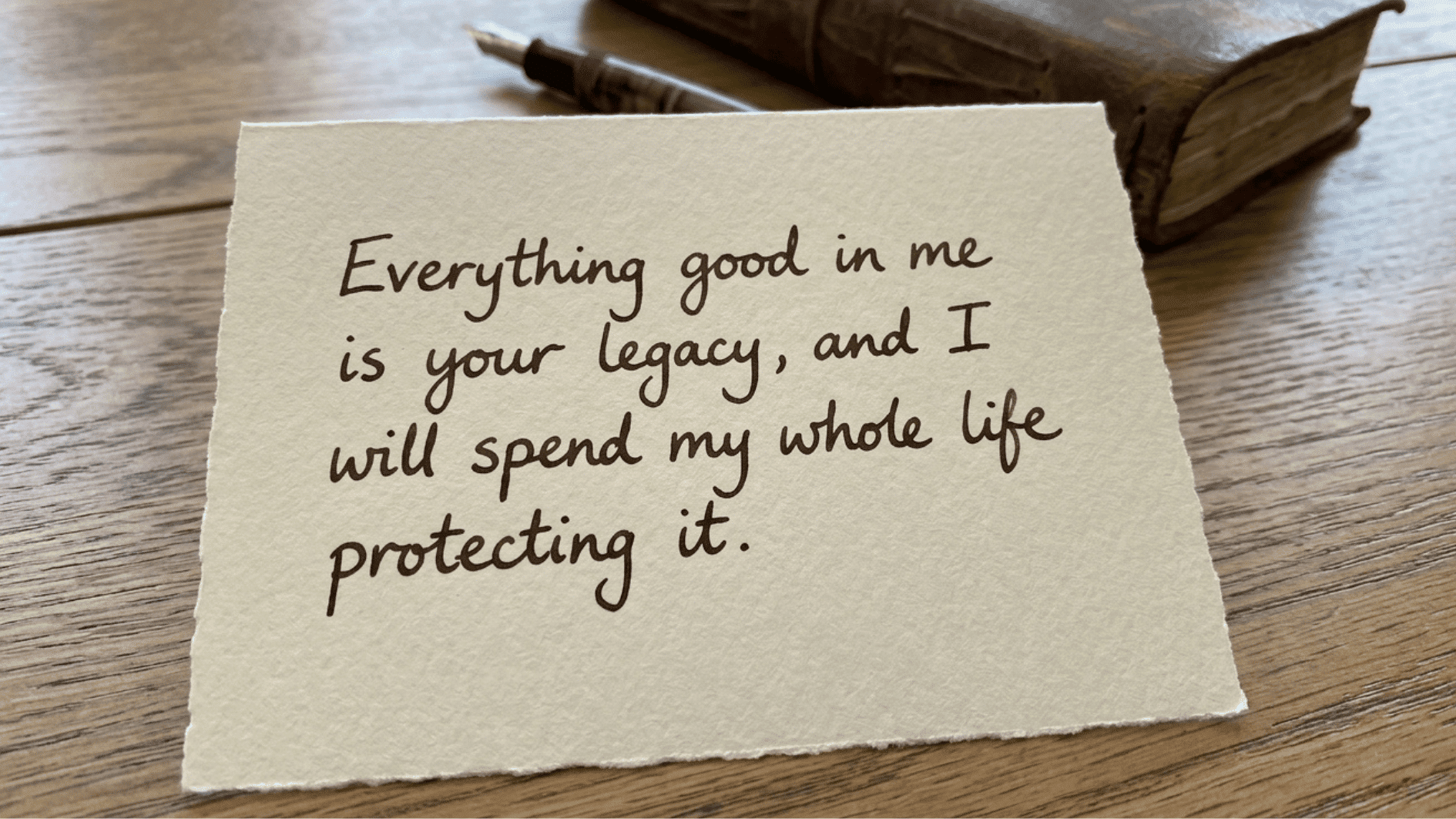 minimal textured card with handwritten message about legacy and love, set on a rustic wooden surface with a journal and pen