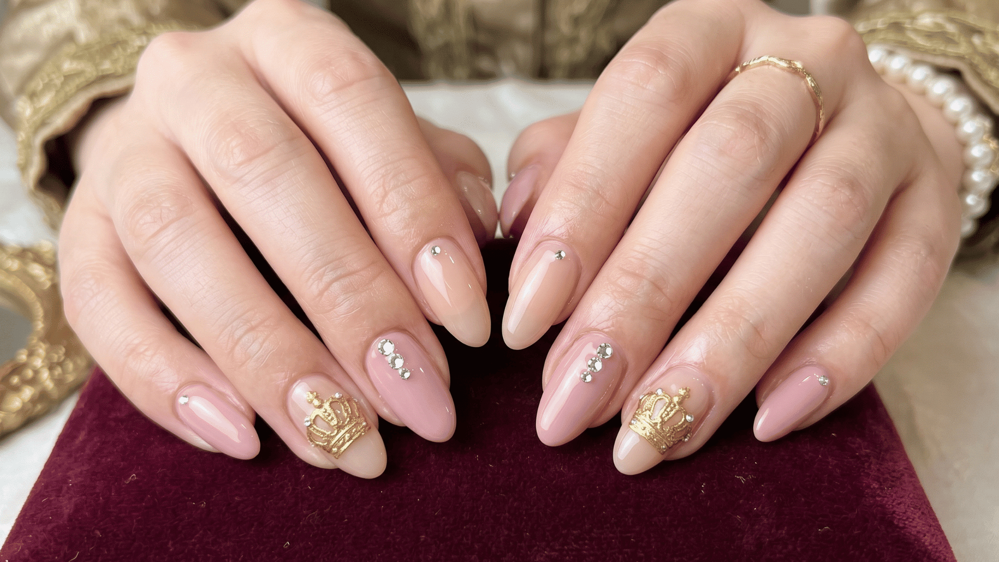 nude and pink nails with gold crown design, rhinestones, elegant royal aesthetic, glossy finish