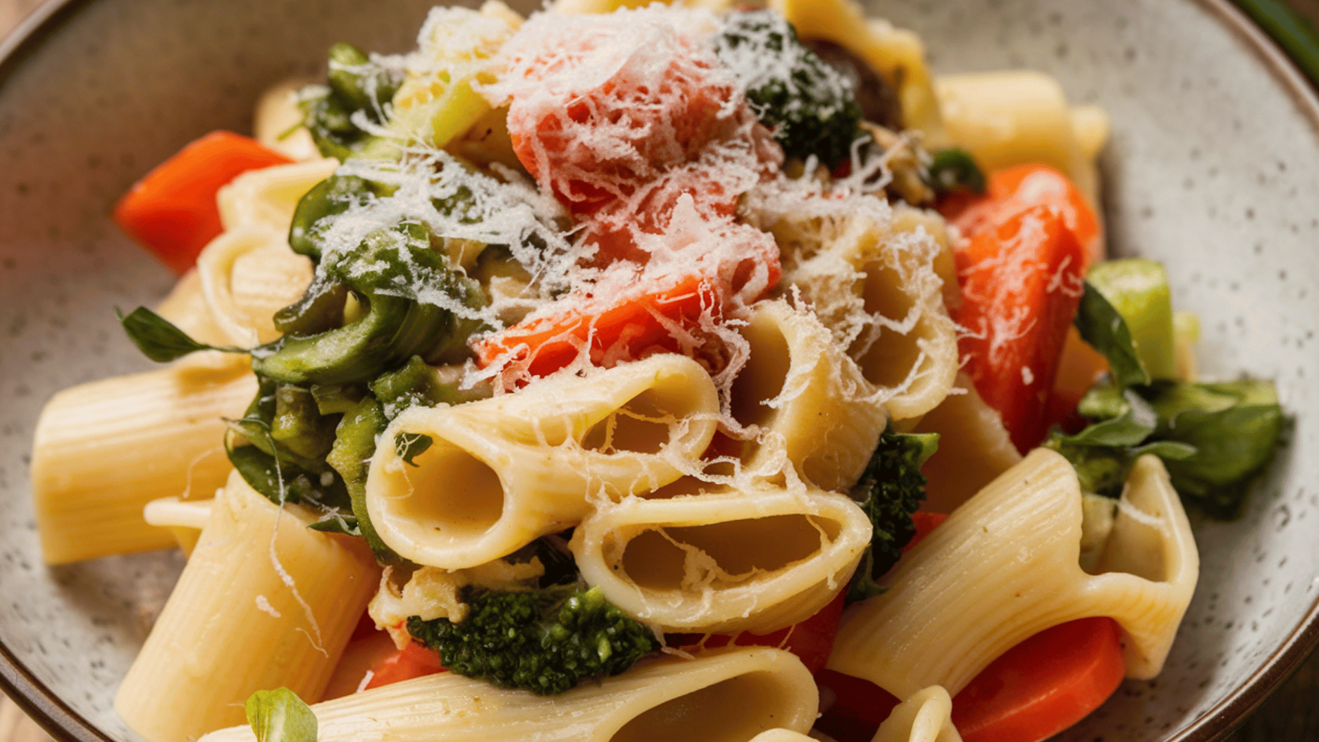 pasta with vegetables and grated cheese in a bowl.