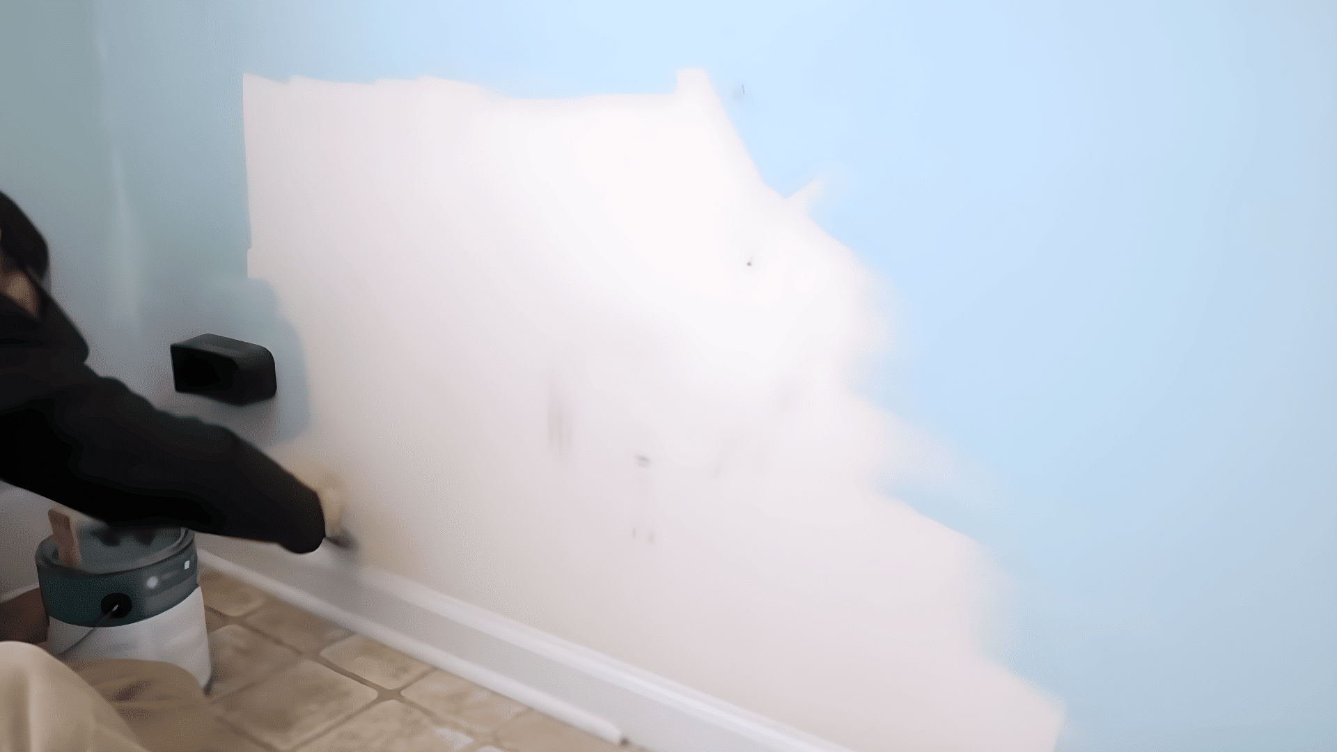 person painting wall after removing appliances before vinyl plank flooring installation.