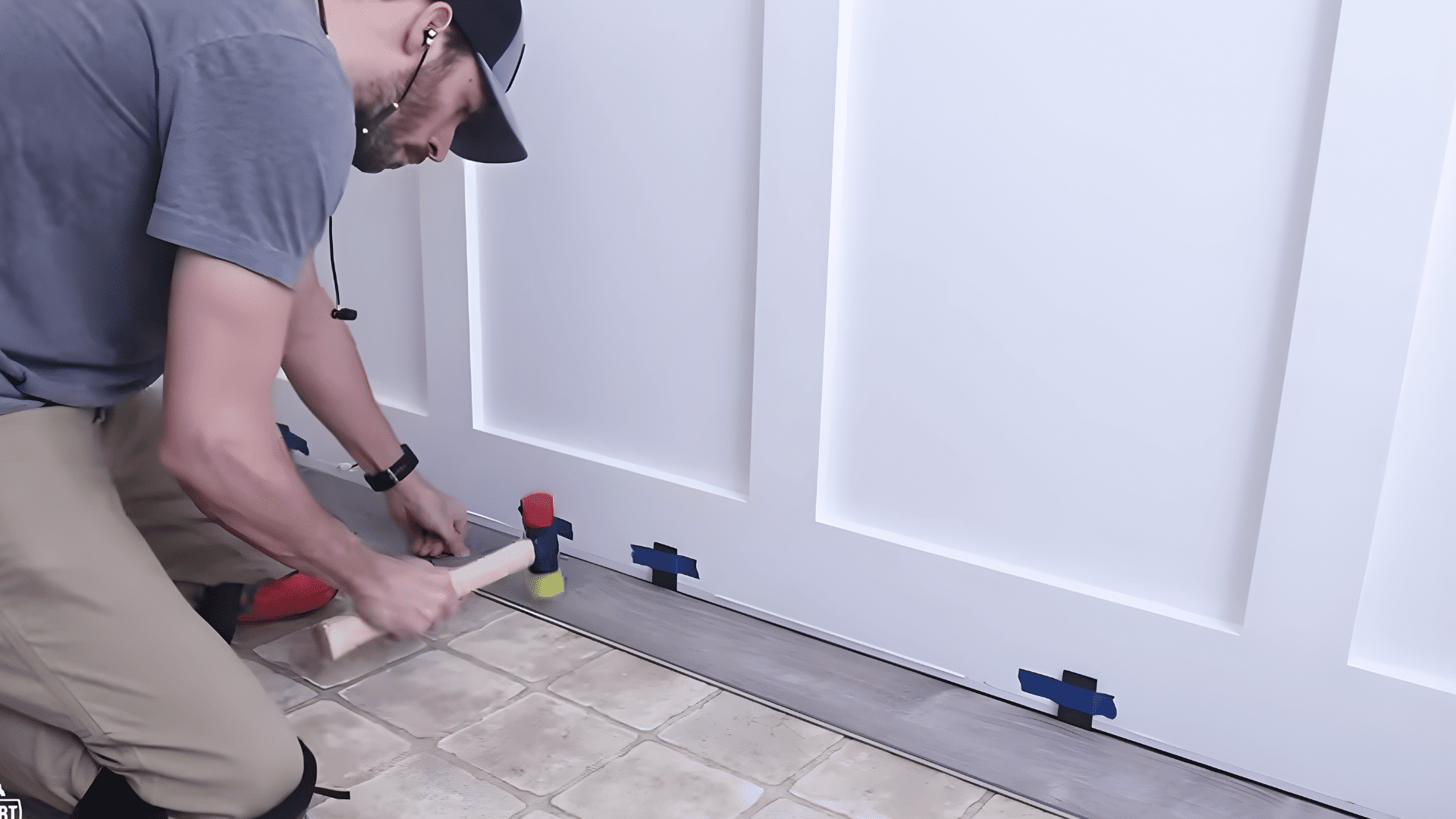 tapping vinyl plank into place using mallet and spacers along wall edge.