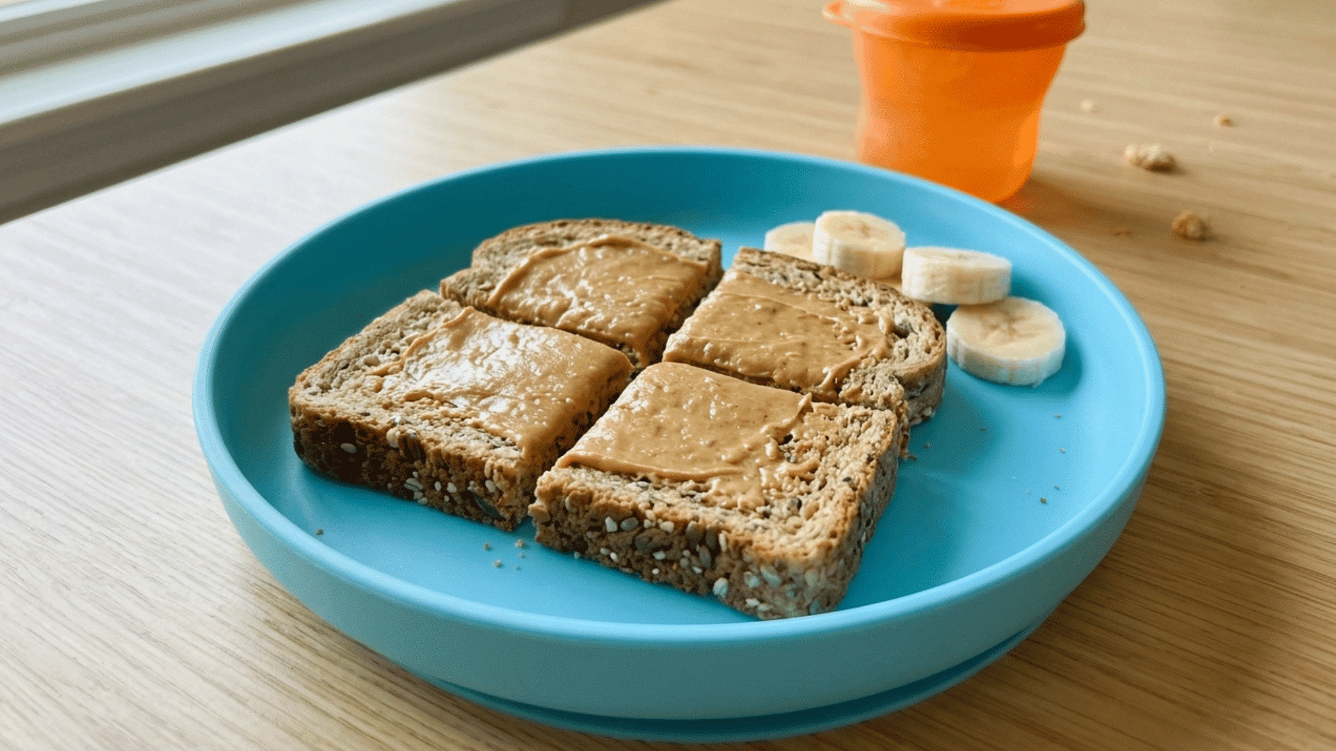 toast squares with peanut butter and banana slices on a blue plate.