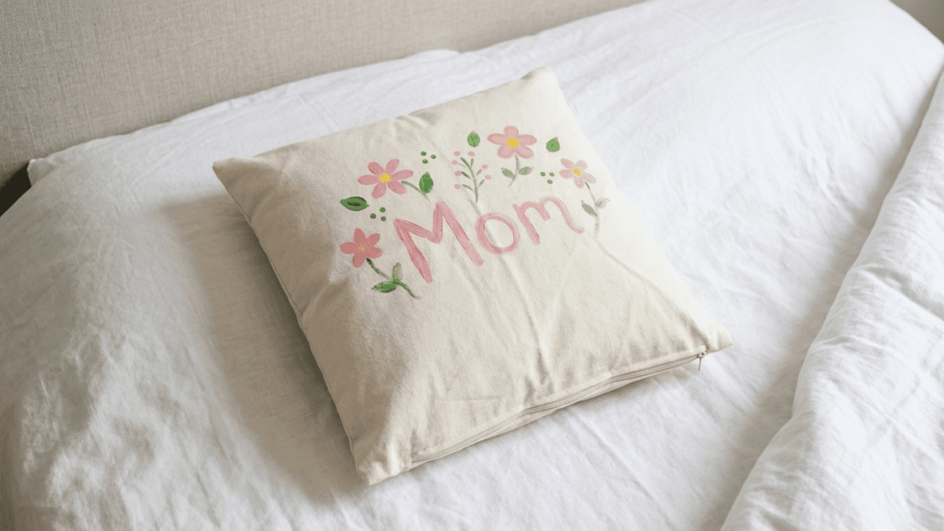 white cushion cover with hand-painted flowers and the word mom in fabric paint made as a diy mothers day gift