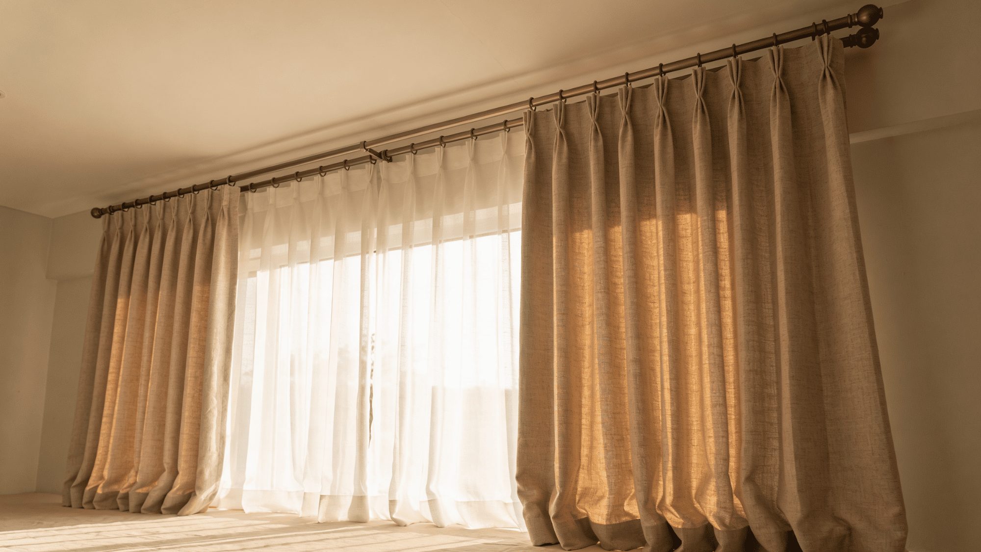 a spare bedroom window with floor-length linen blackout panels, sheer underlayer, and ceiling-mounted rods