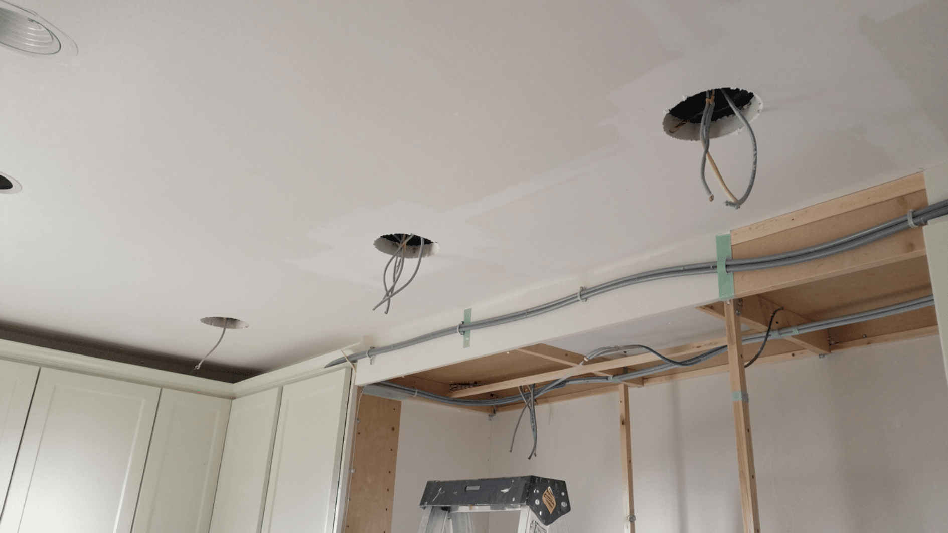ceiling electrical wiring setup for recessed lights in kitchen renovation with ladder and unfinished construction area