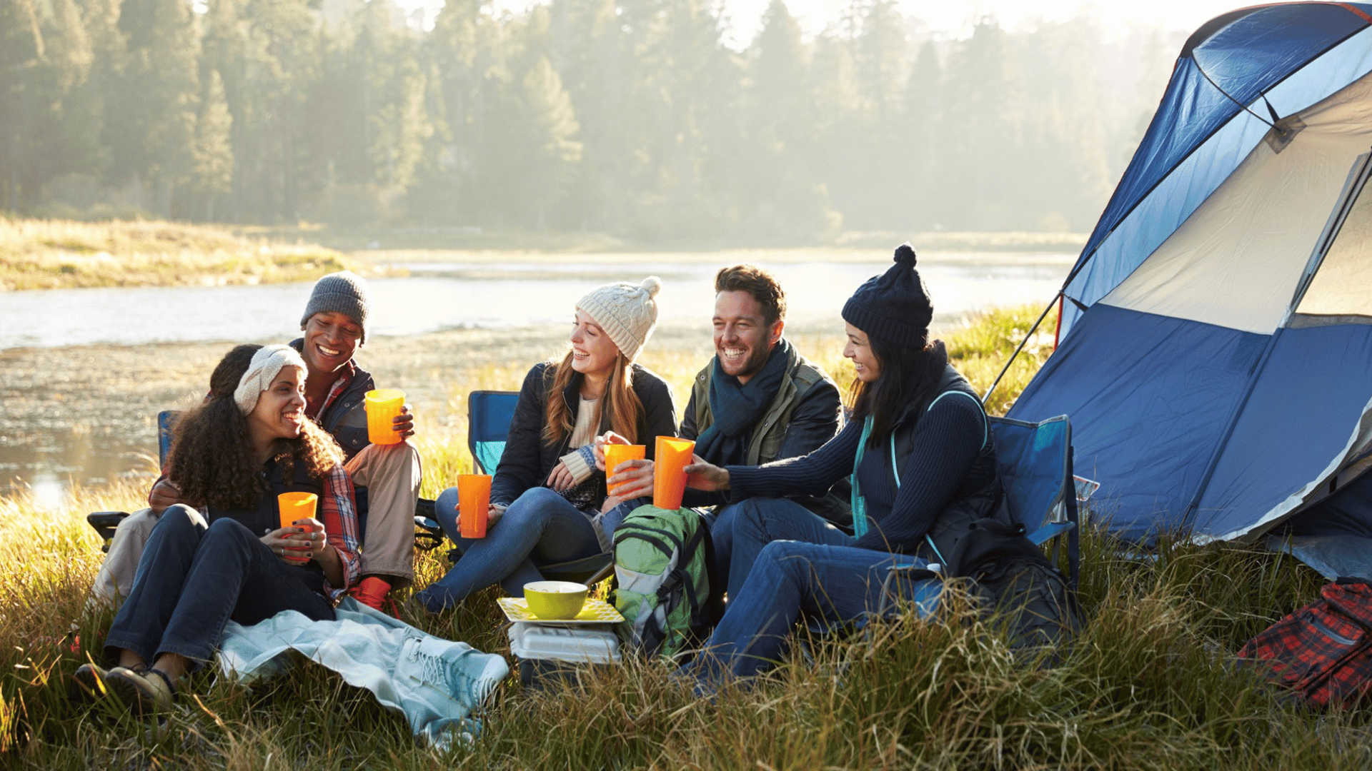 family camping beside a lake with a tent, campfire, and peaceful sunset during memorial day weekend
