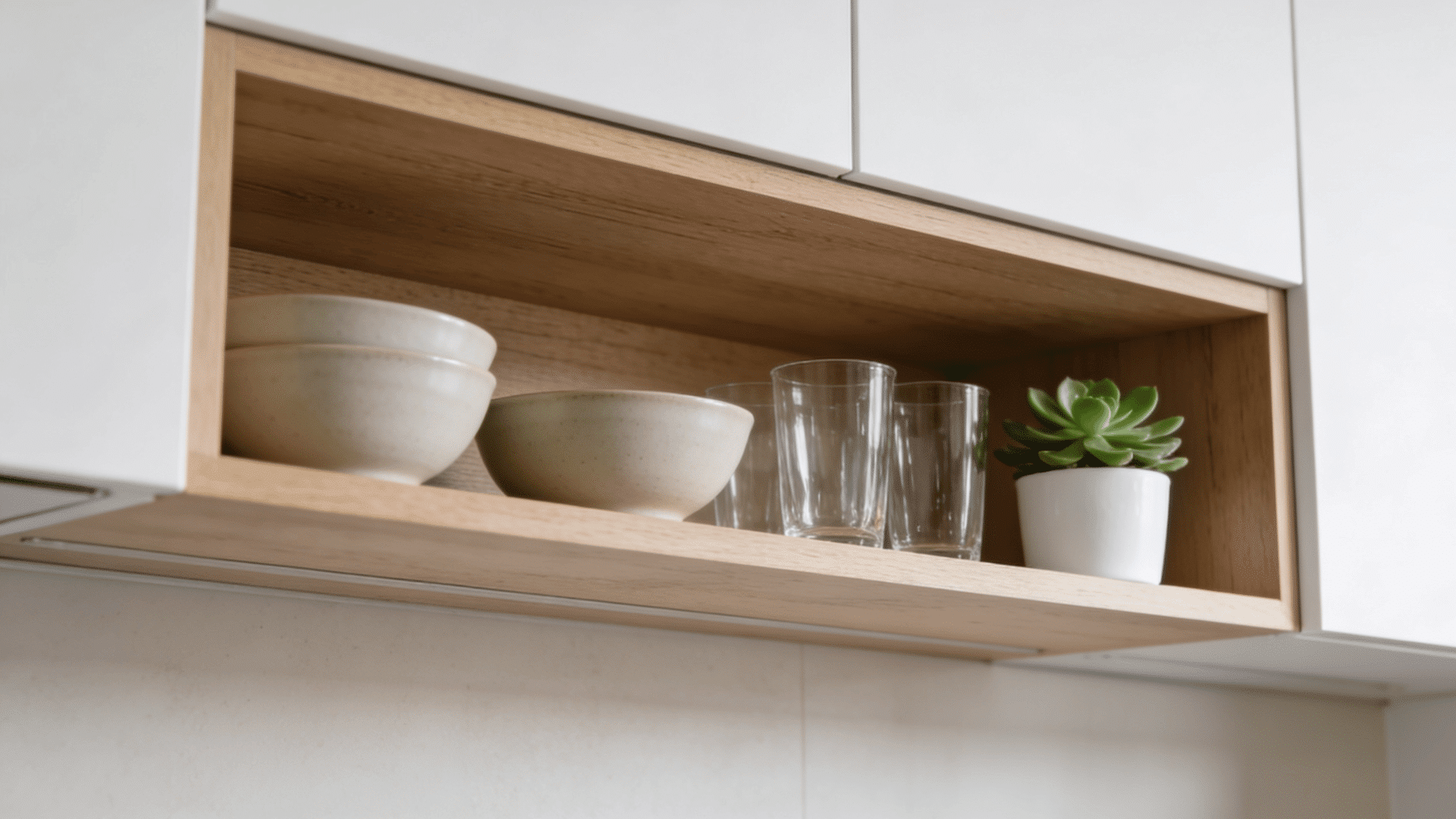 minimal open kitchen shelf with ceramic bowls glass cups and small green succulent in wooden cabinet
