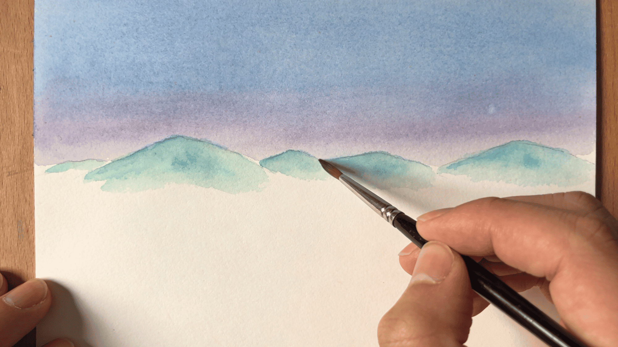 painting distant mountains using watercolor technique with fine detail brush on canvas