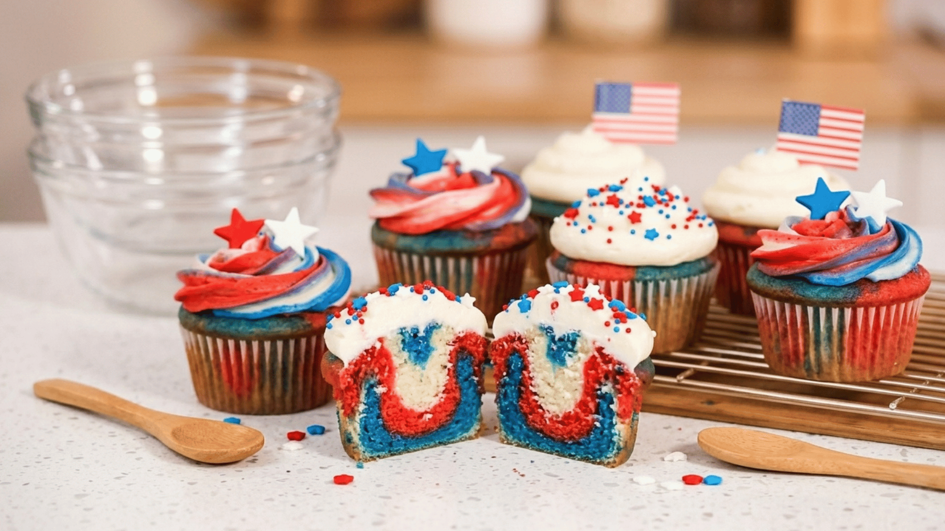 red, white, and blue cupcakes with colorful frosting and patriotic sprinkles on a rack.