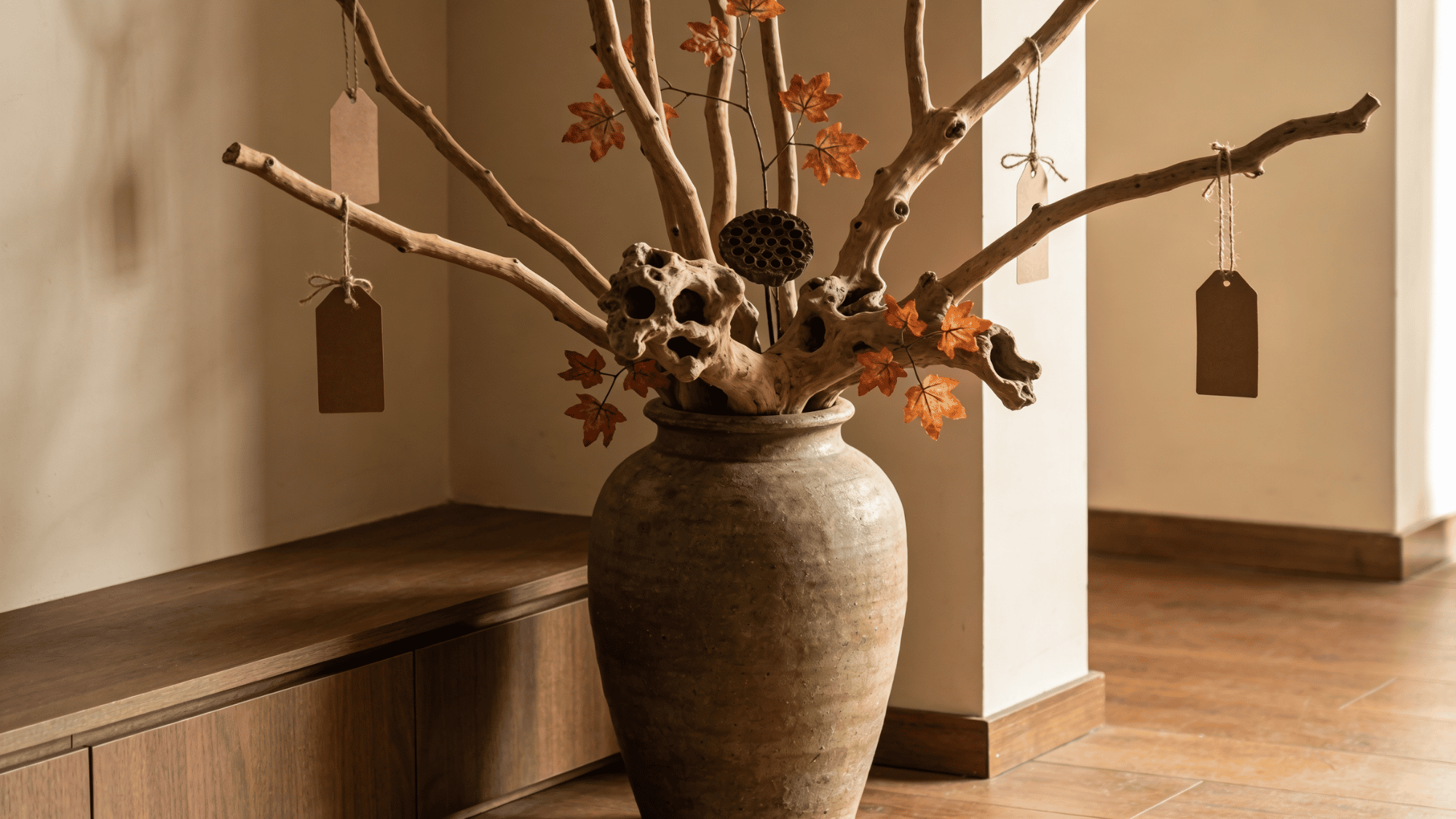 tall dried branches with hanging faux leaves and twine tags in a ceramic vase as fall natural home decor
