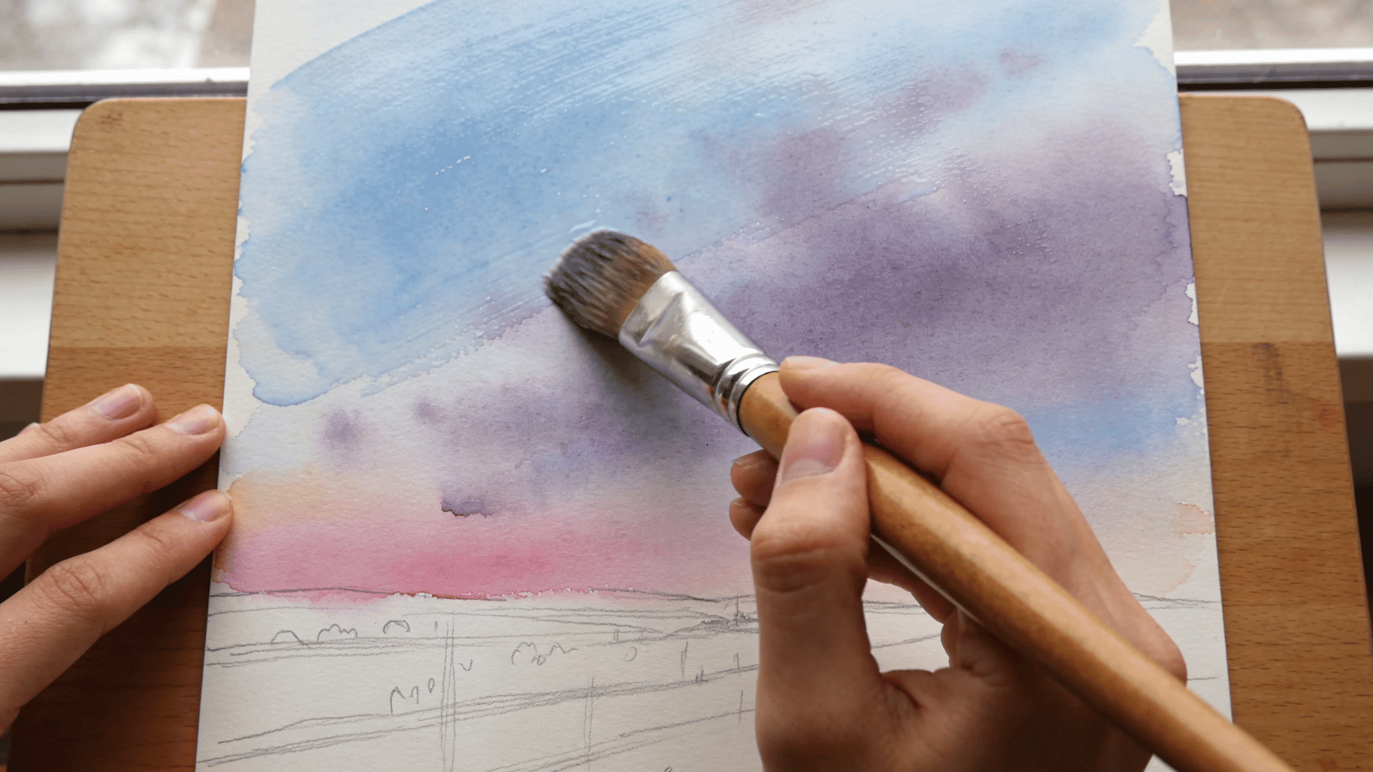 watercolor painting process with soft sky colors and brush strokes on textured paper