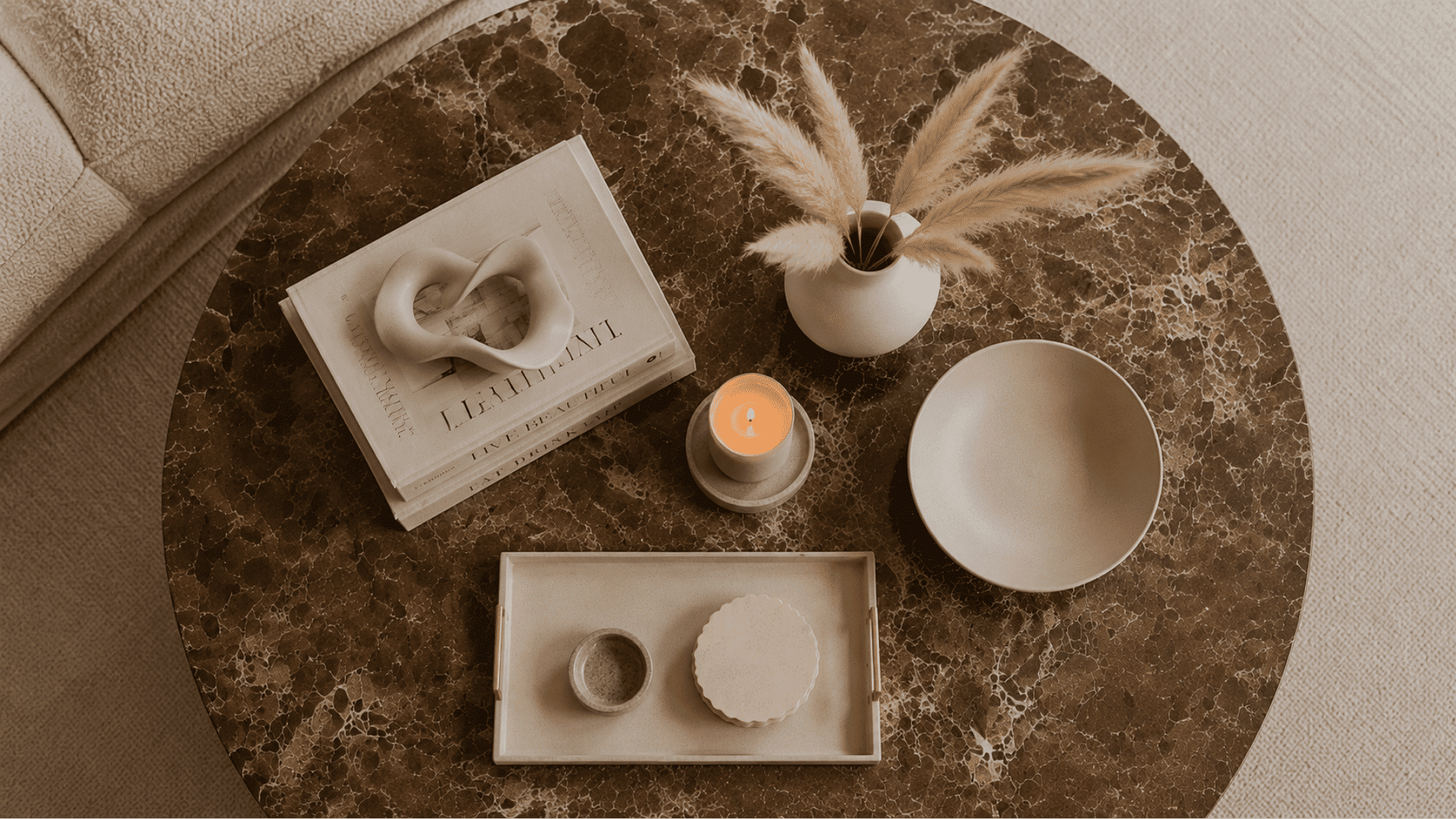 Aerial view of a round marble coffee table styled with books, candle, tray and ceramic bowl