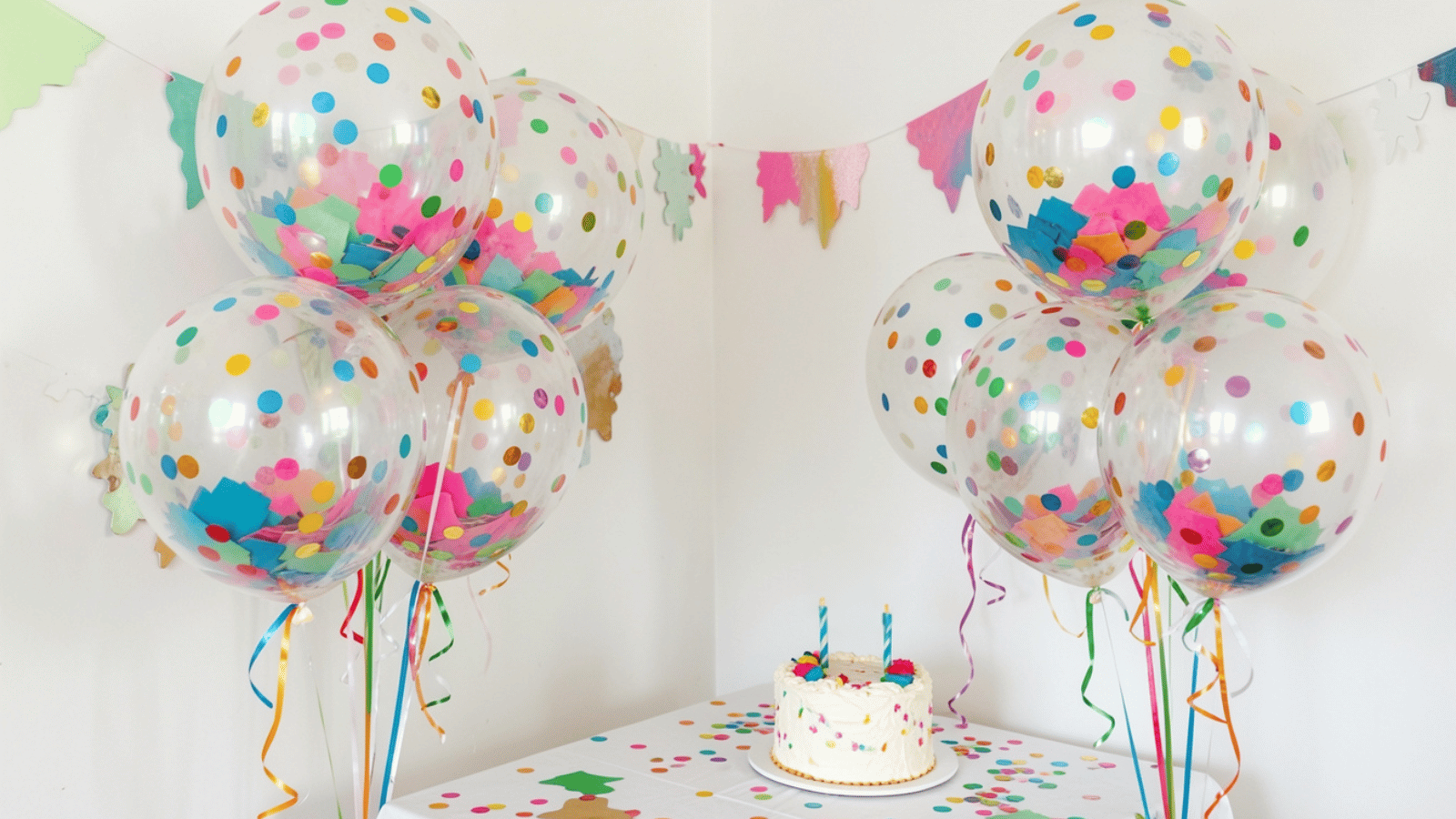 Clear confetti balloons grouped beside a birthday dessert table.