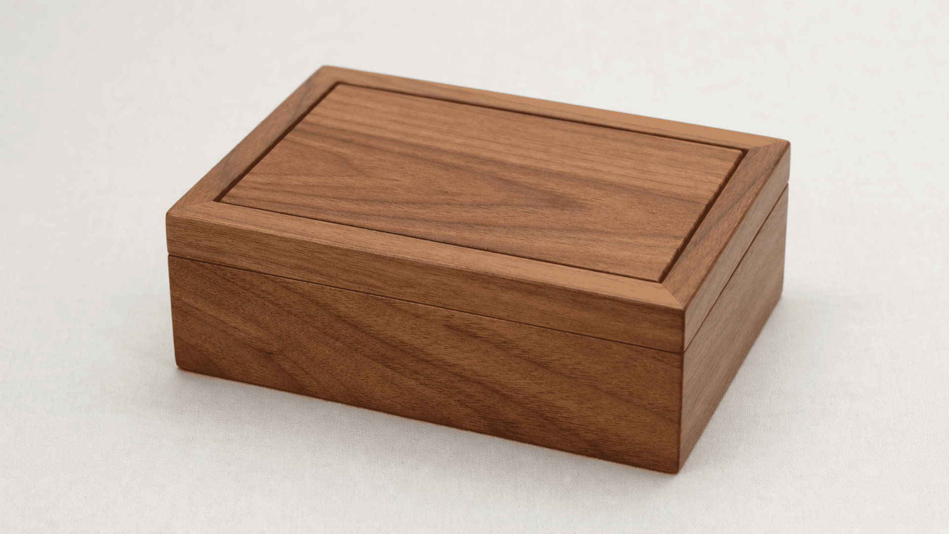 finished small wooden gift box made from smooth natural wood panels, clean rectangular shape with simple lid design, soft matte finish, placed on a neutral light surface with soft indoor lighting