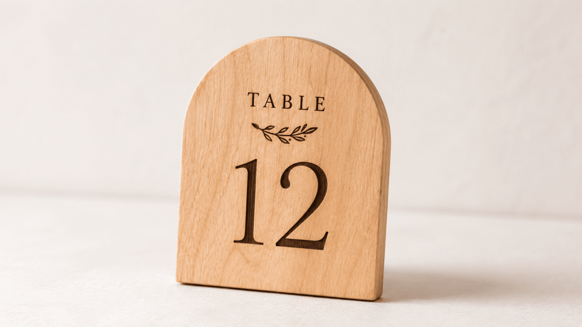 finished wooden table number board made from smooth natural wood with clean engraved or painted number design, light matte finish, placed on a simple neutral surface with soft indoor lighting