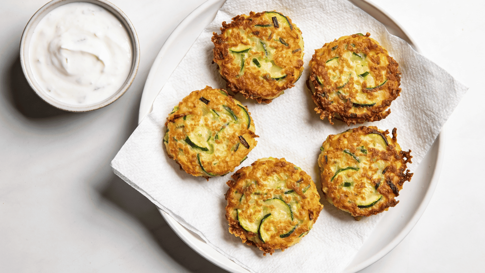 golden zucchini fritters with crispy edges on white plate with yogurt dip, healthy quick meal ideas for kids