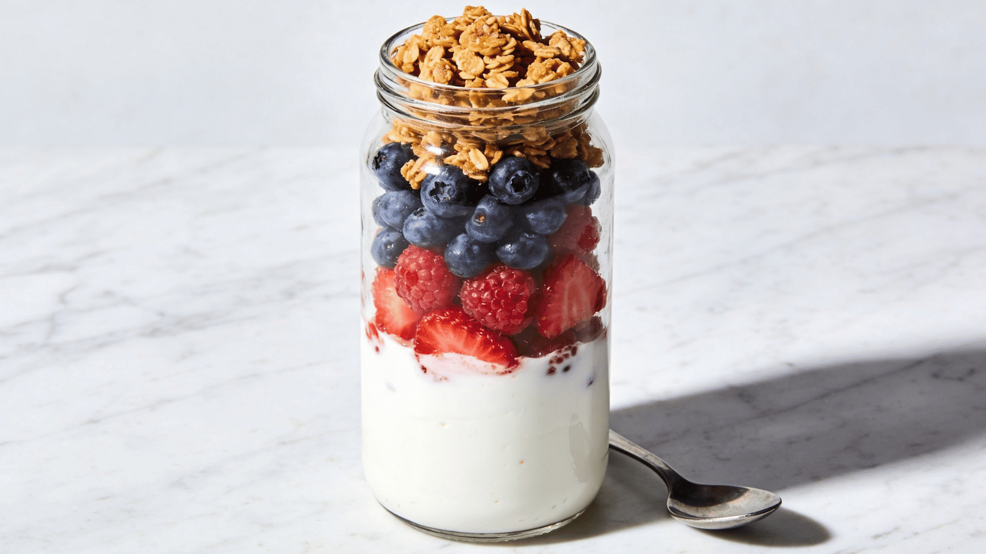 _greek yogurt parfait in glass jar with mixed berries and granola, healthy breakfast meal idea for kids