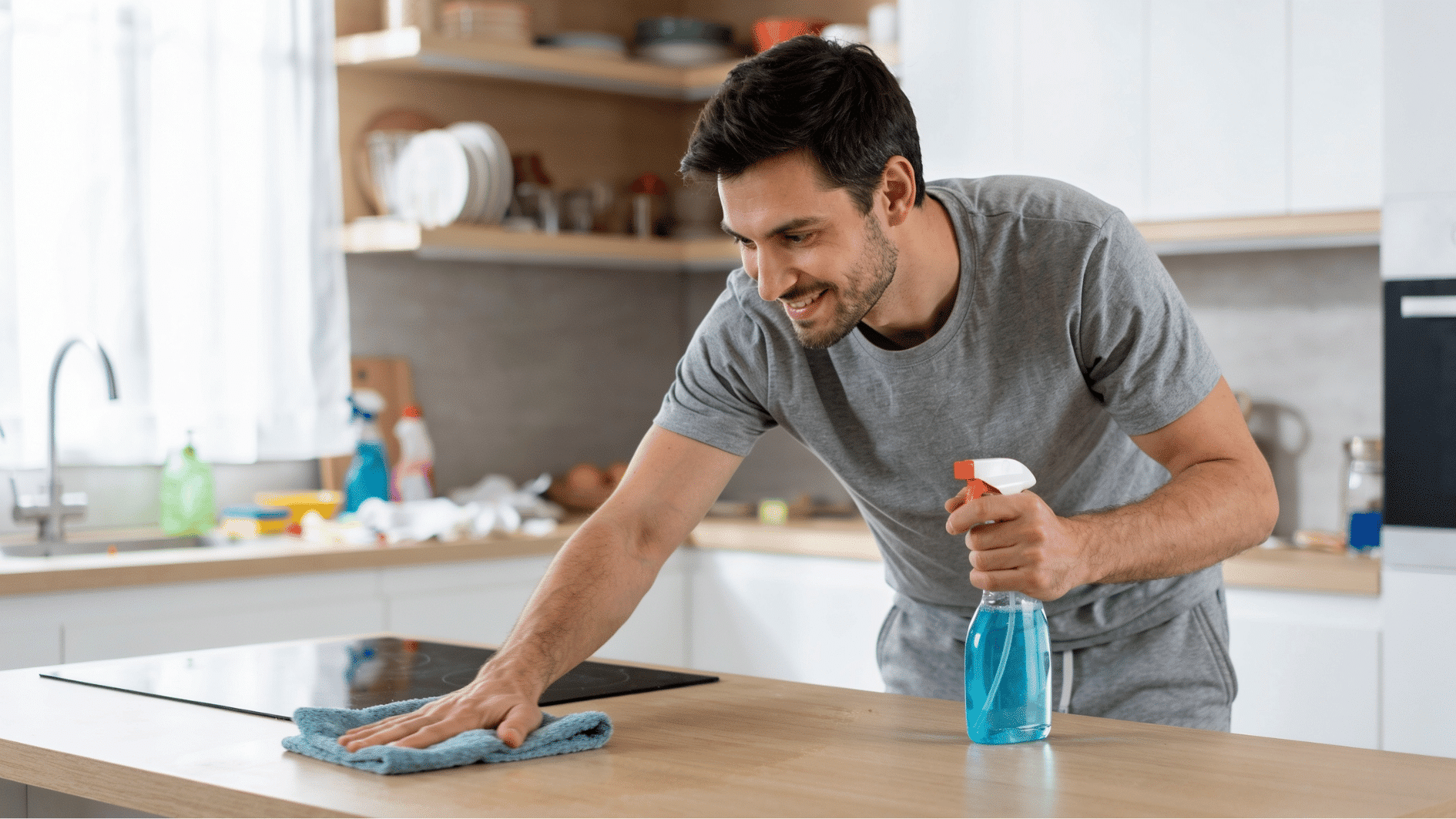 man cleaning kithcen counter with liquid cleaning spray and soft towel