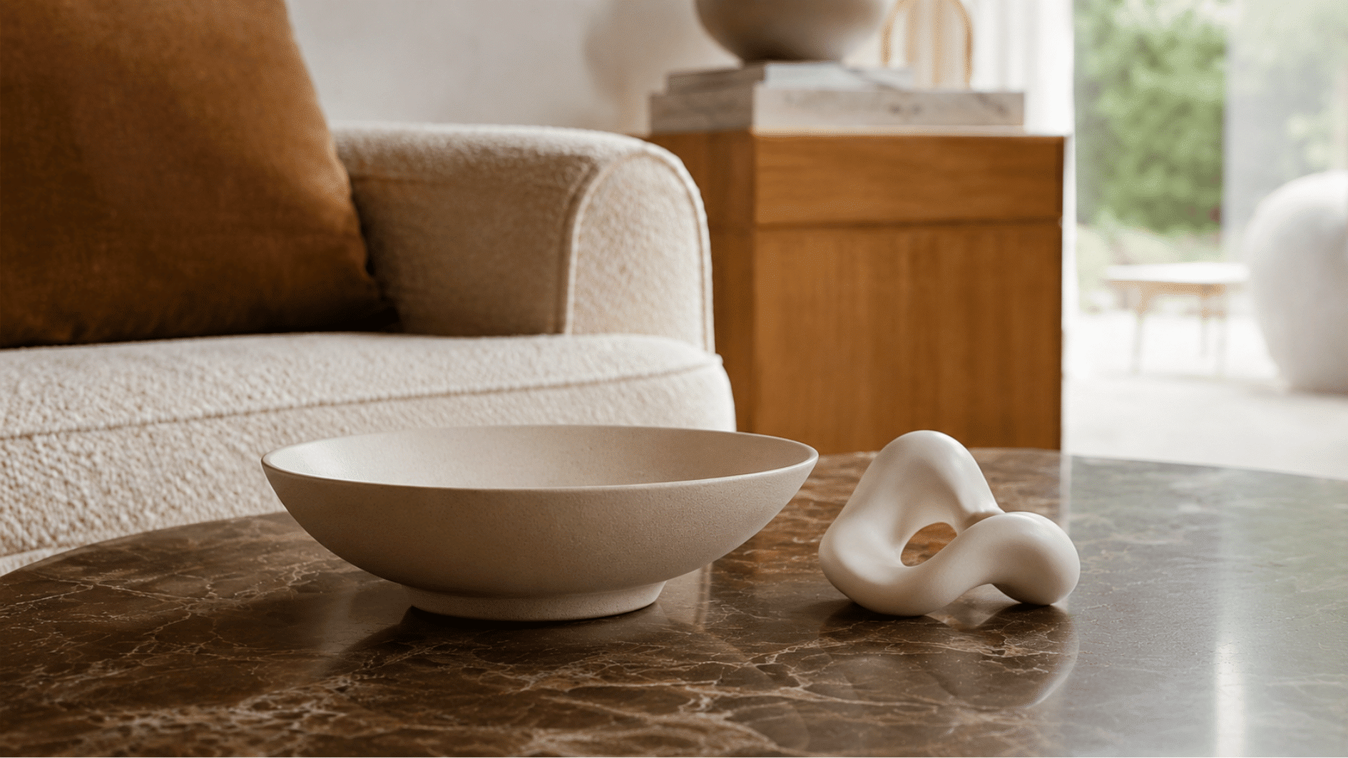 Matte ceramic bowl and abstract white sculpture on a dark marble coffee table