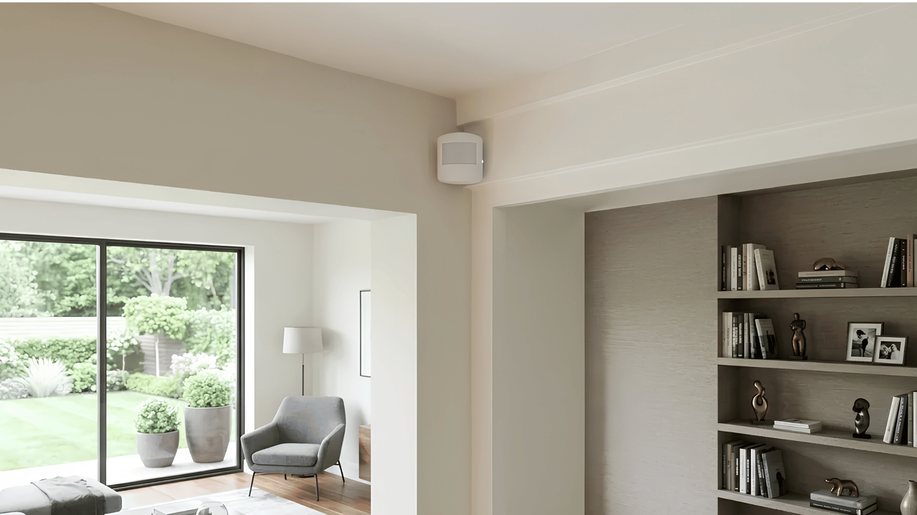 motion sensor mounted high on interior wall overlooking spacious living area with bookshelves and garden access