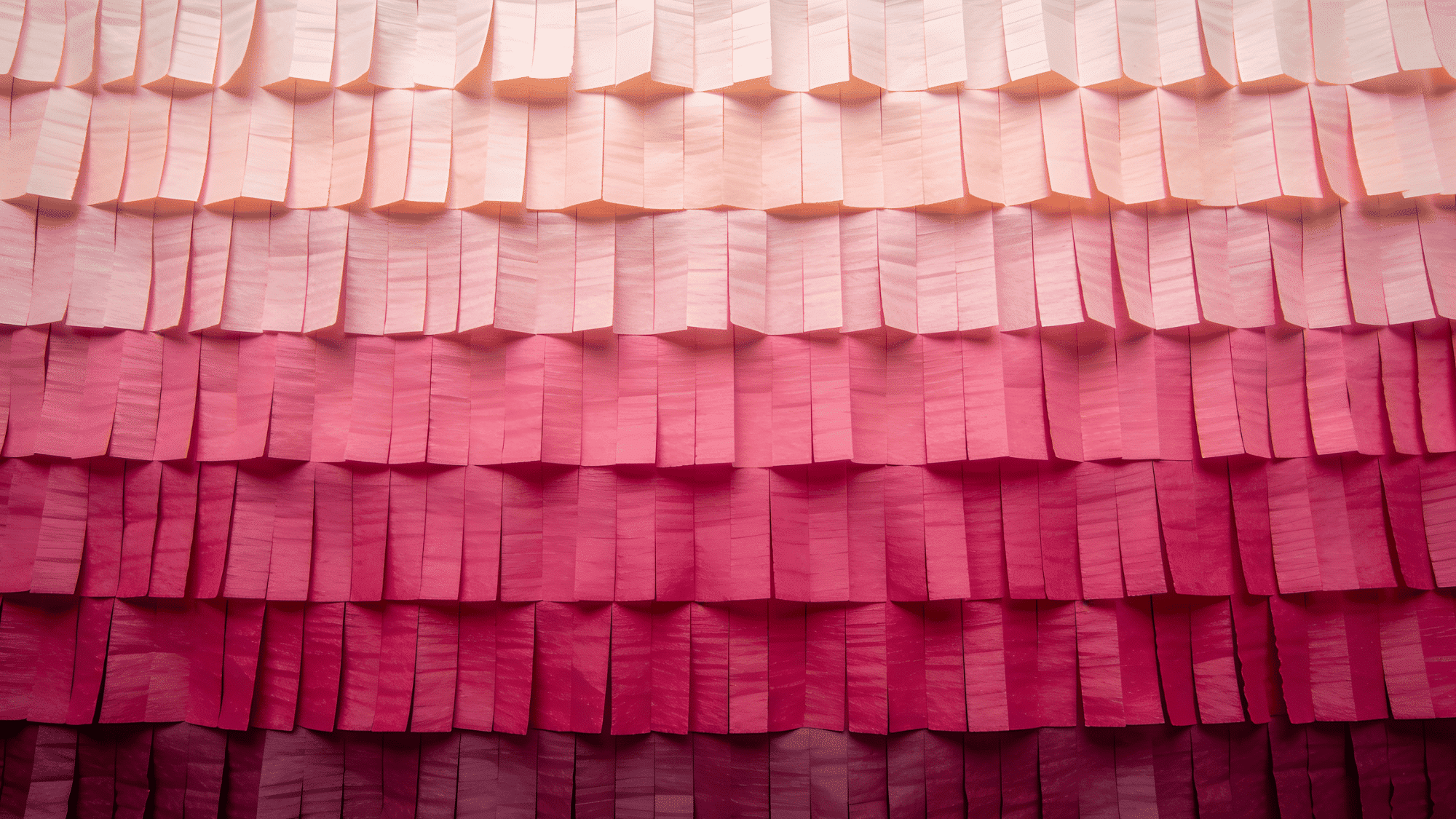 ombre streamer wall with crepe paper rows fading from pale blush at the top to deep magenta at the bottom