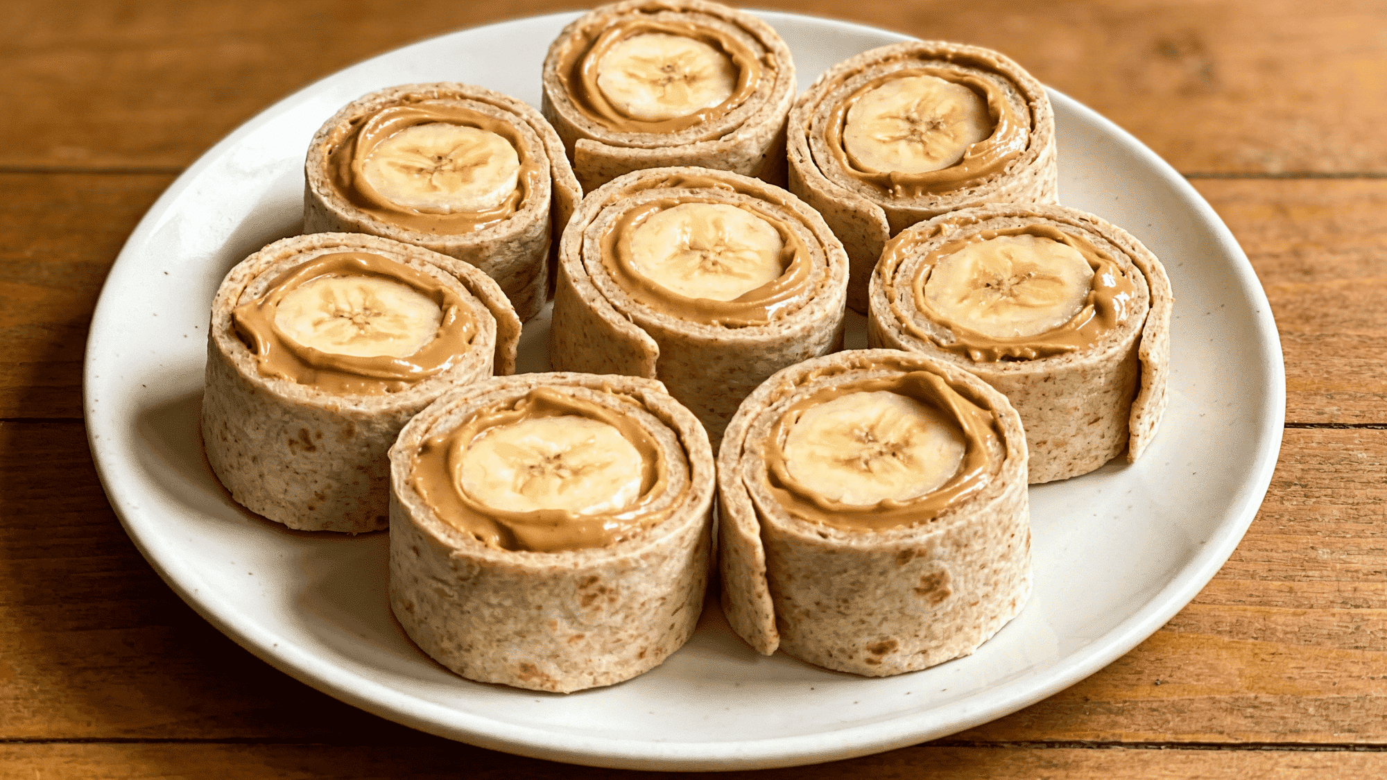 peanut butter banana roll-up slices on white plate with spiral cross-section, quick healthy snack for kids