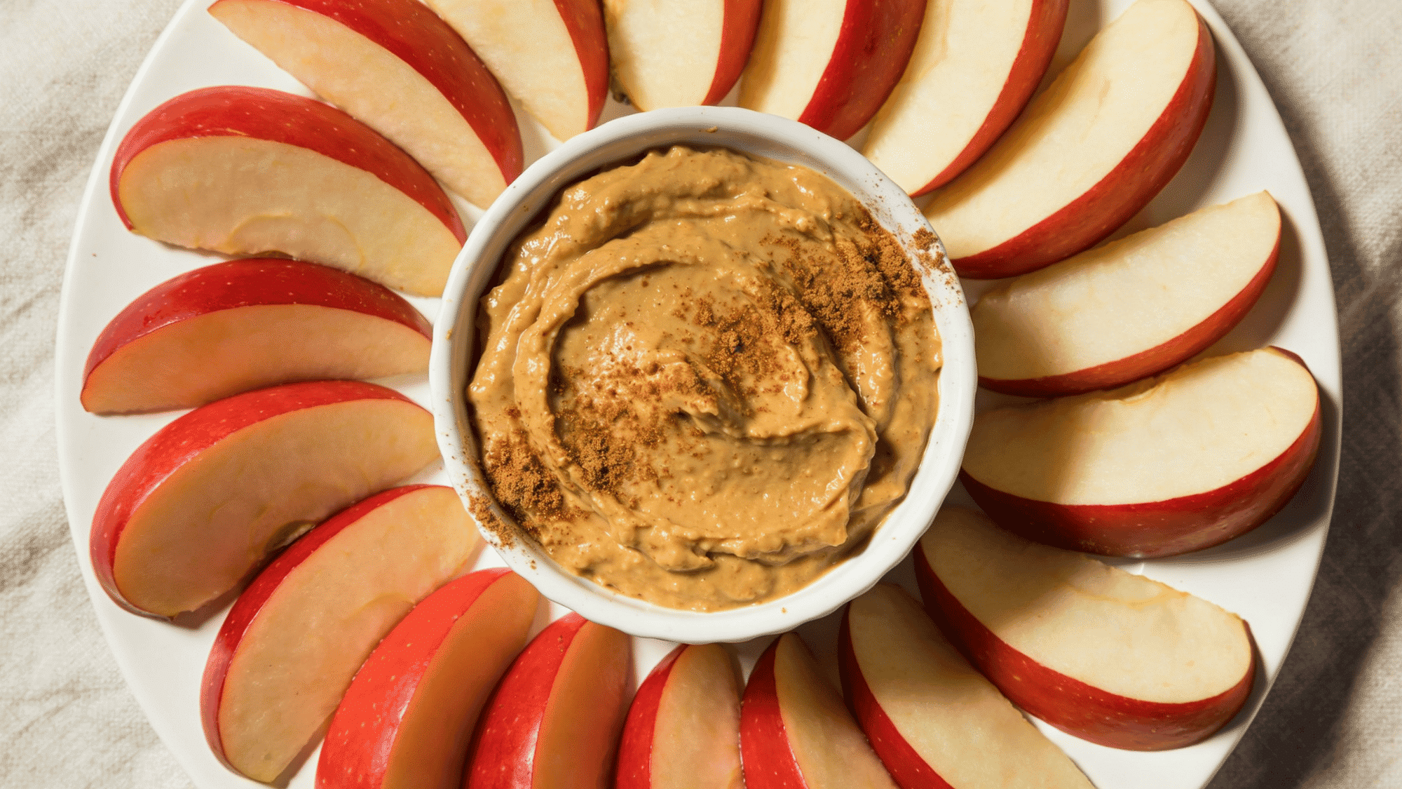 red apple slices fanned around ramekin of almond butter with cinnamon, healthy quick snack meal ideas for kids